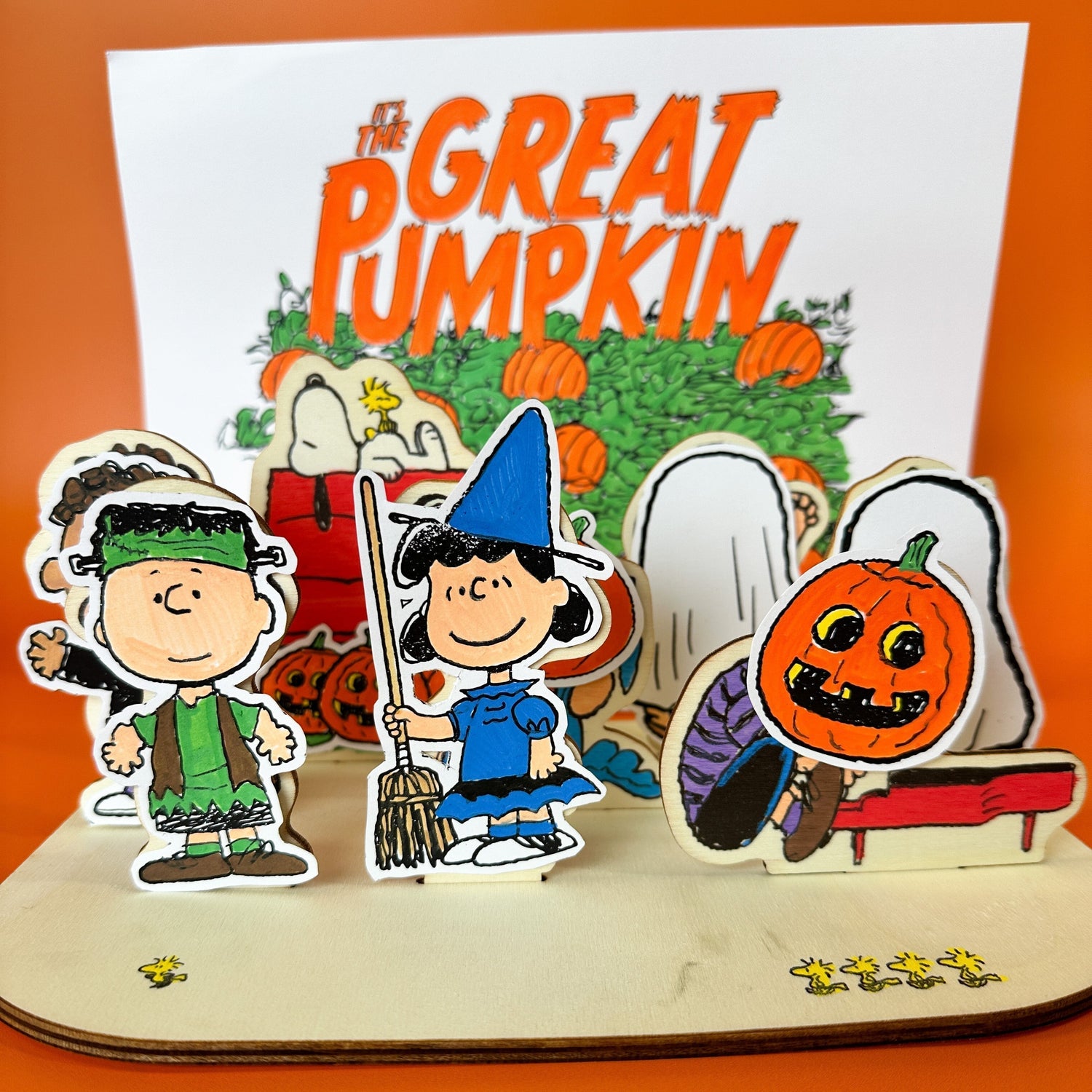 Completed OOLY x Peanuts Halloween Color-In Wooden Scene Kit with characters in costumes and “It’s The Great Pumpkin” backdrop.