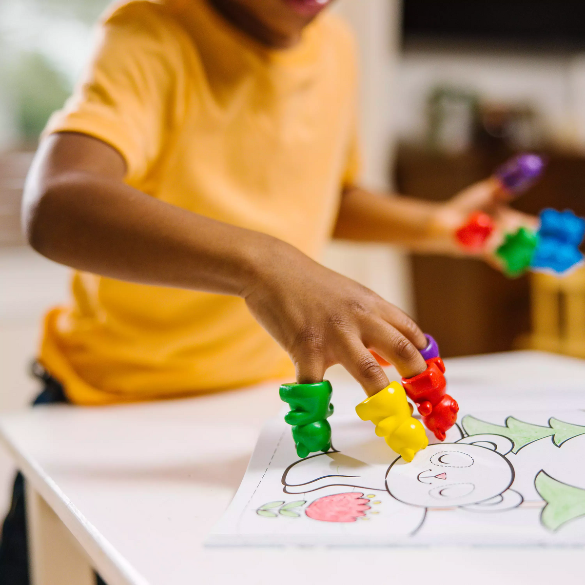 Child coloring with Cuddly Cubs bear finger crayons on coloring book