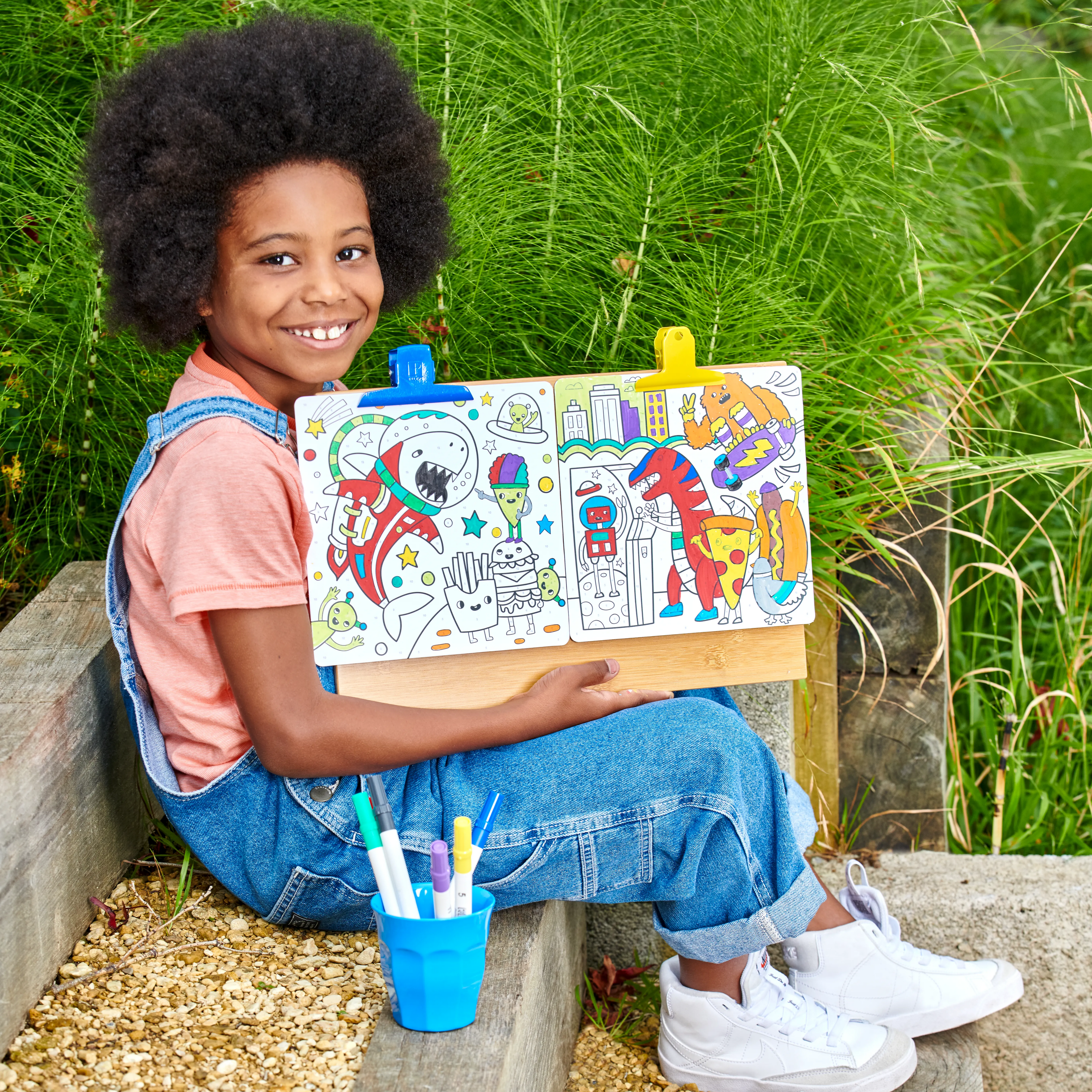 Kid showing off painted art cards from OOLY Colortopia Color By Number Paint Marker Kit - Epic Adventures set