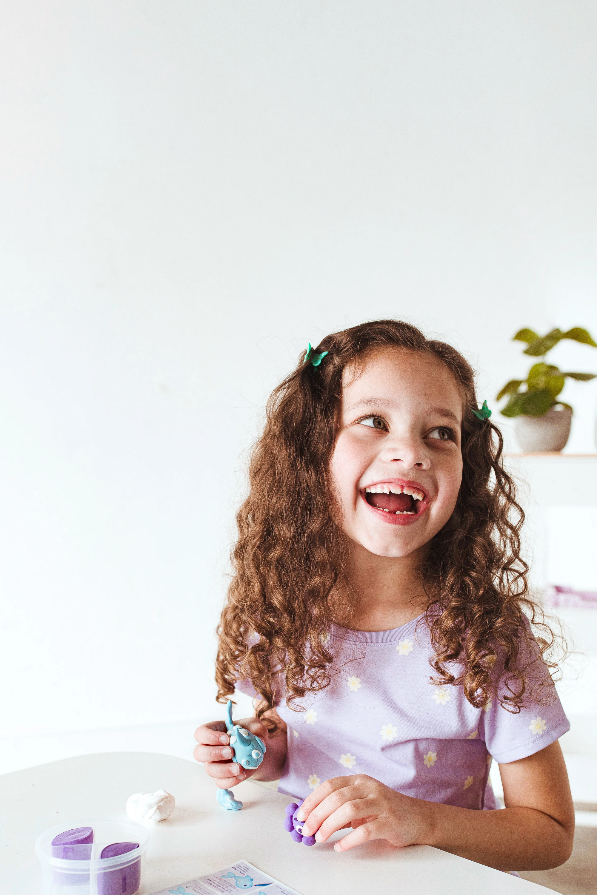 Girl laughing while building clay from OOLY Creatibles Mini Air Dry Clay Kit - Ocean BFFs