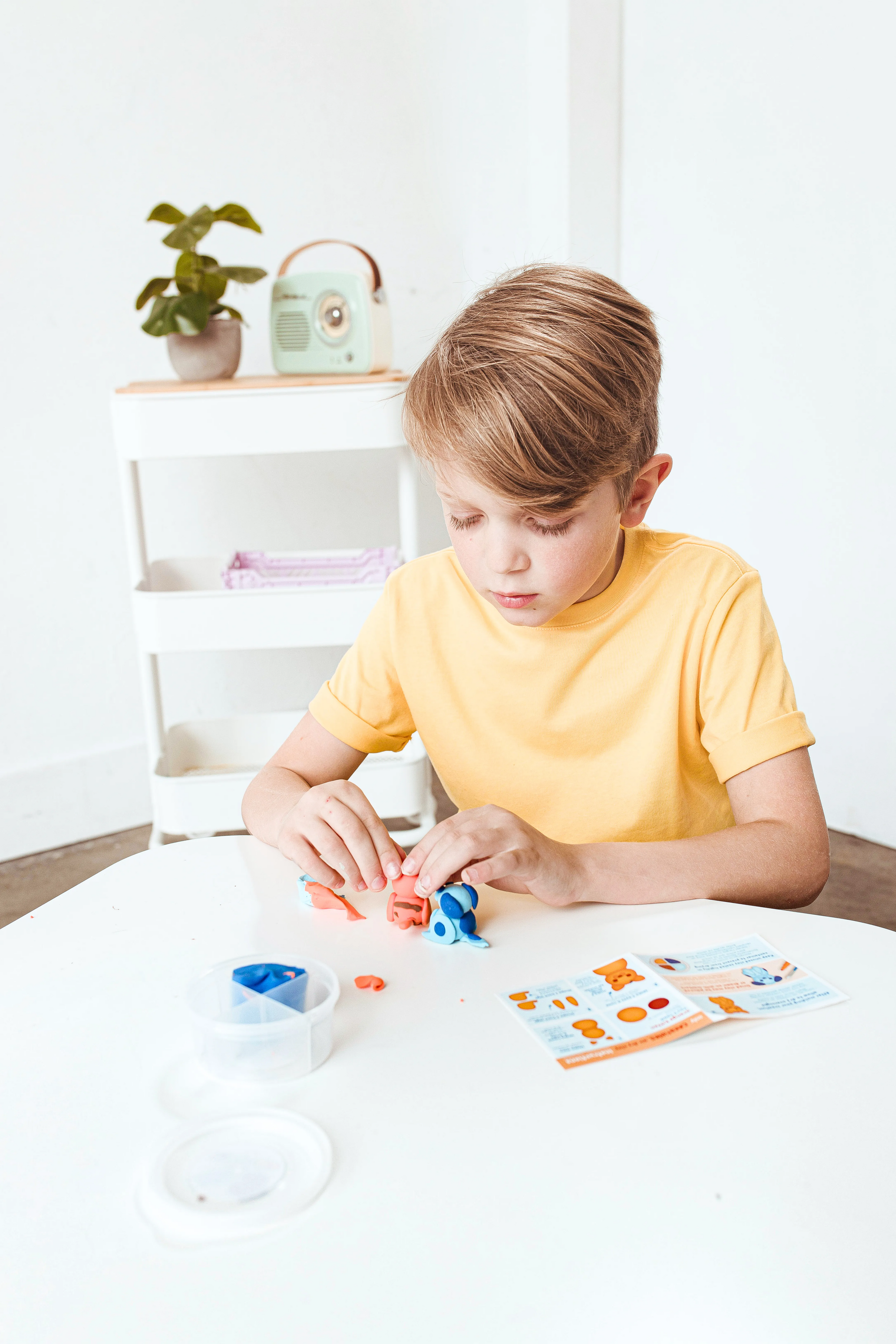 Boy making clay cat and dog from OOLY Creatibles Mini Air Dry Clay Kit - Pet BFFs