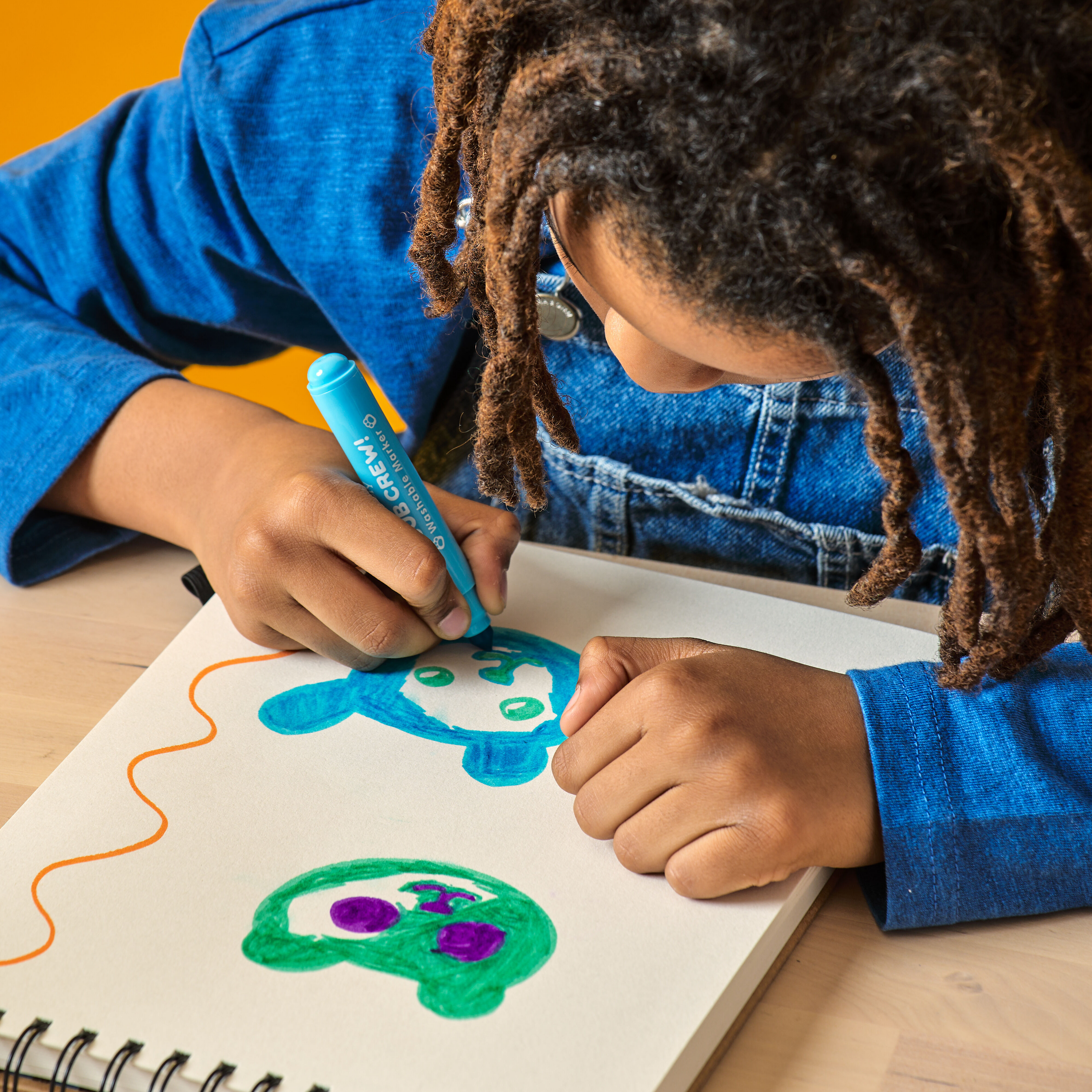 Kid coloring bears in a sketchbook with OOLY Cub Crew Washable Markers on a wooden table