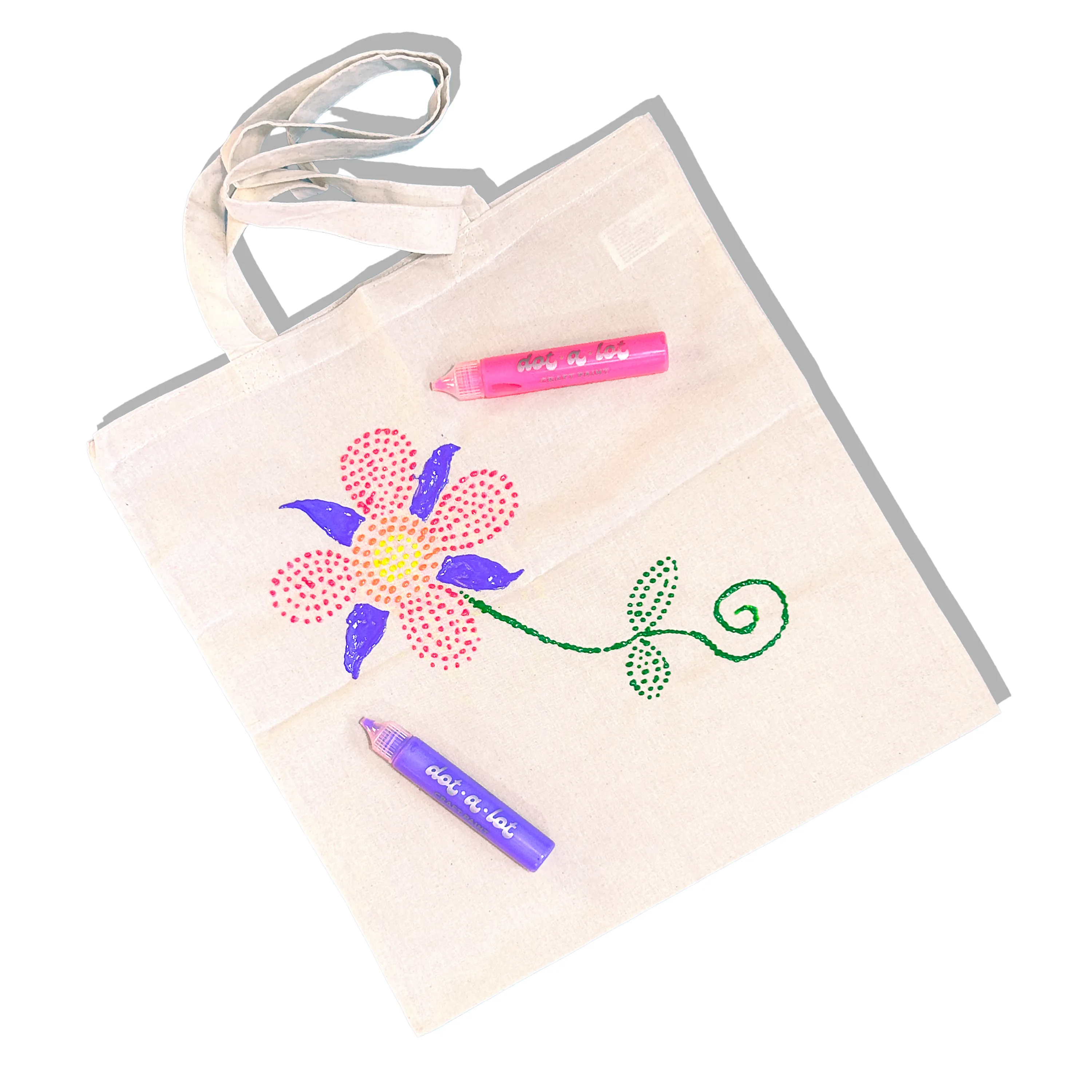 Beige tote bag with a colorful flower design decorated with OOLY Dot-a-Lot 3D Dimensional Craft Paint and two paint sticks on a white background