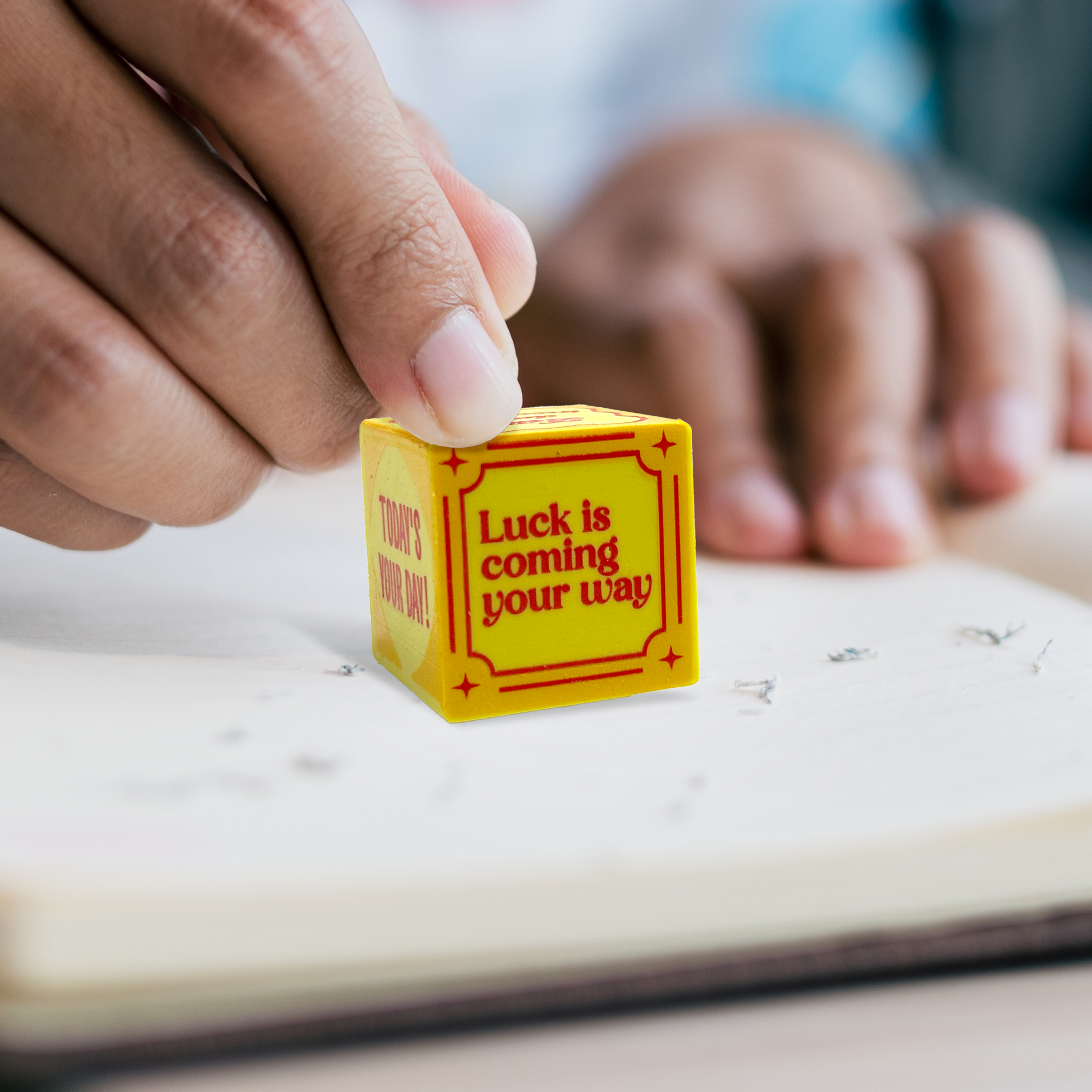 Close up of hand holding "luck is coming your way" yellow die from OOLY Feeling Lucky Dice Erasers.