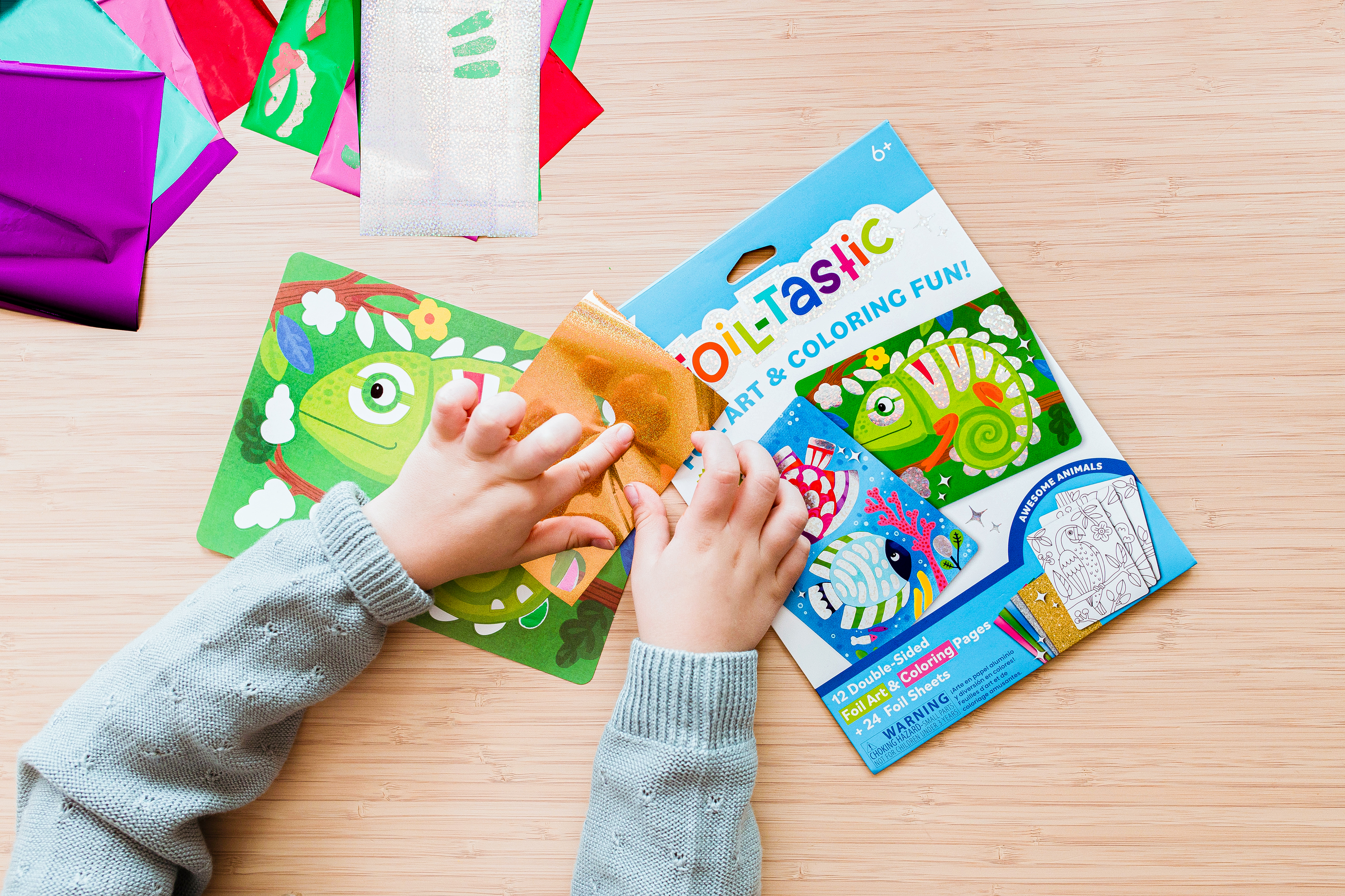Kid pressing orange foil sheet from OOLY Foil-Tastic foil art set