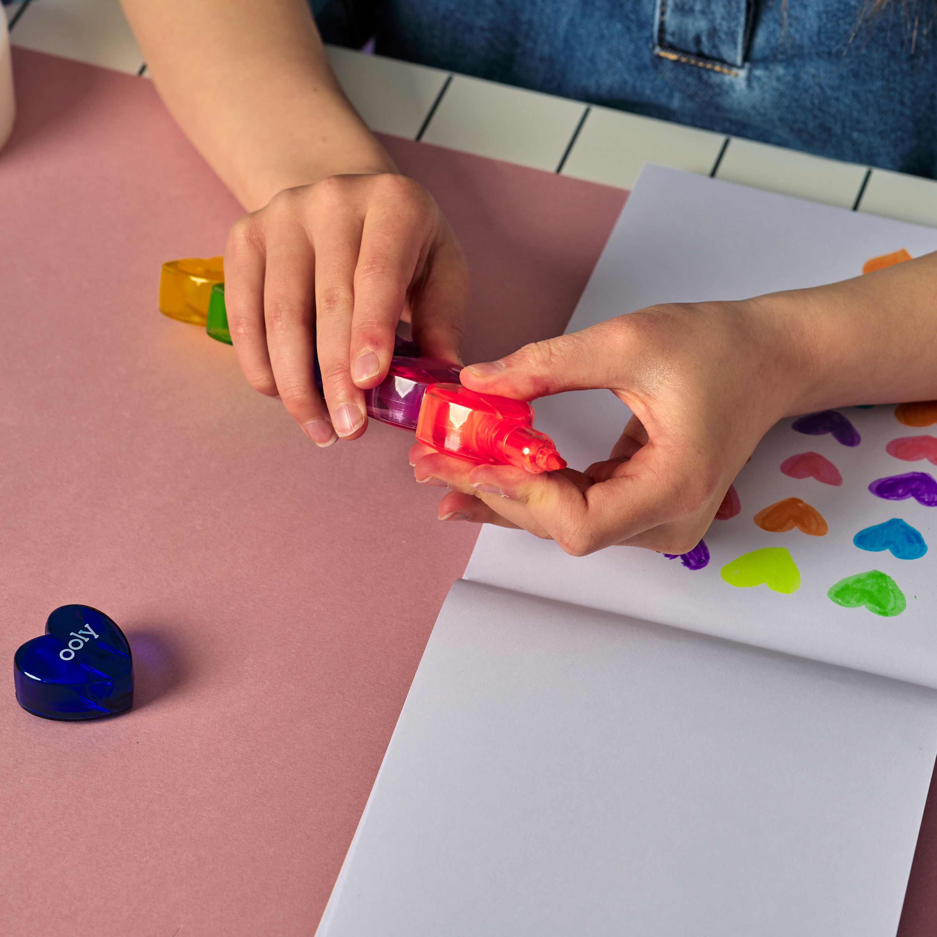 Girl disconnecting OOLY Heart Stacks Stacking Highlighters with a sketchpad with colored hearts