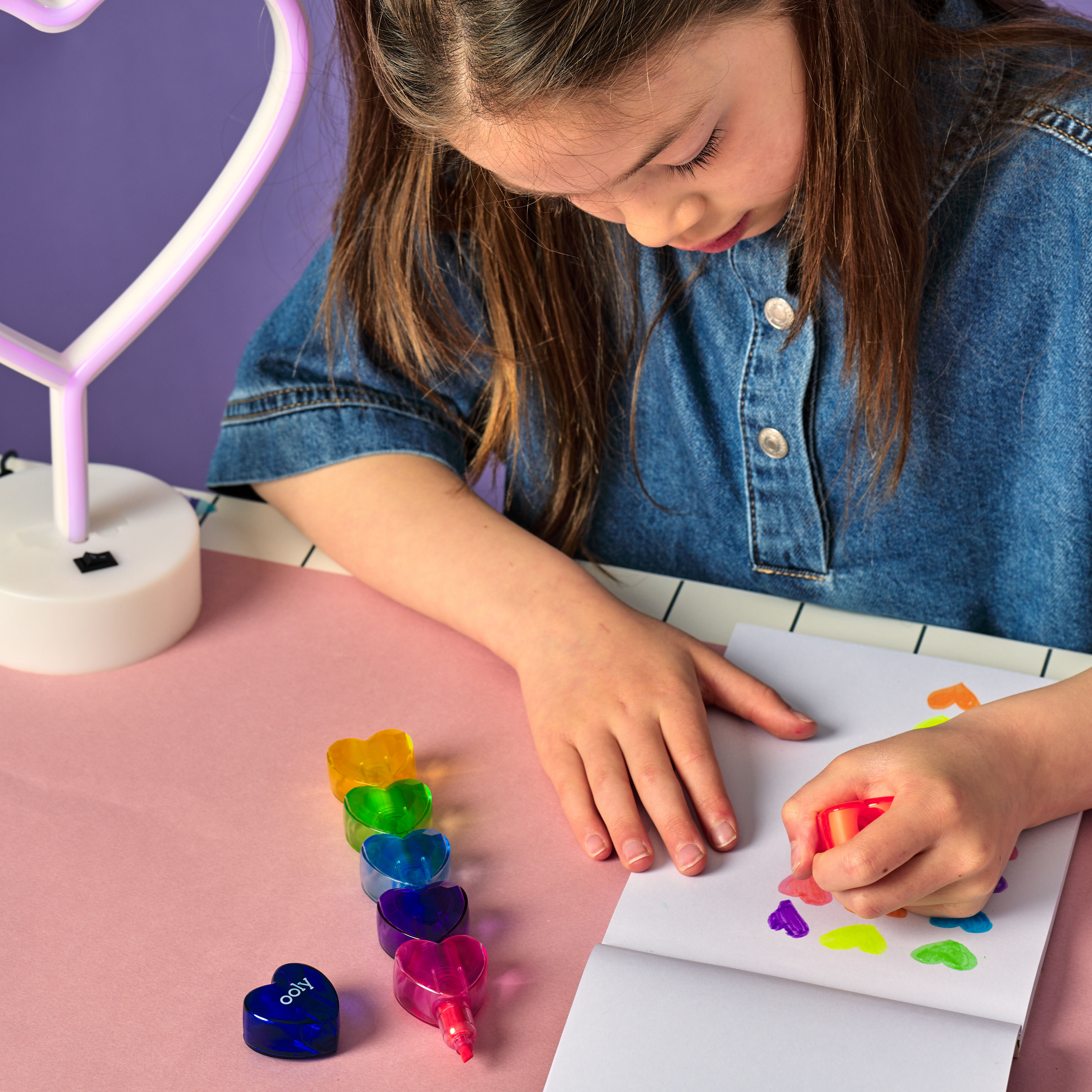Girl coloring hearts in a sketchpad with OOLY Heart Stacks Stacking Highlighters