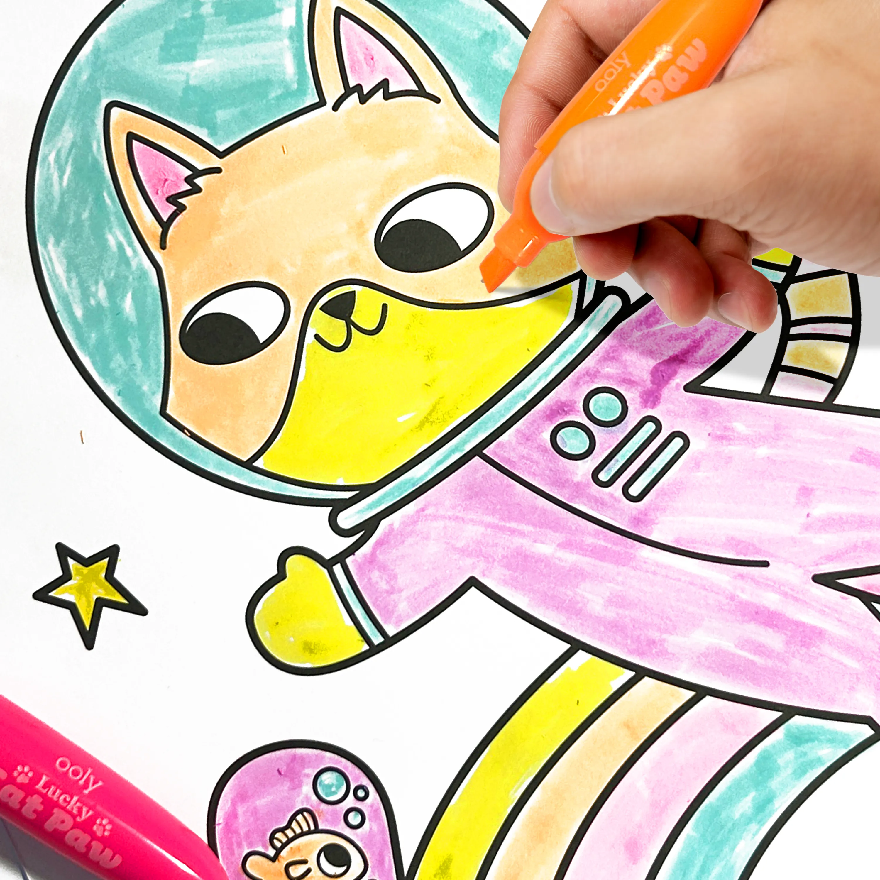 Close of of kid coloring a coloring page of an astronaut cat with an orange OOLY Lucky Cat Paw Scented Neon Highlighter