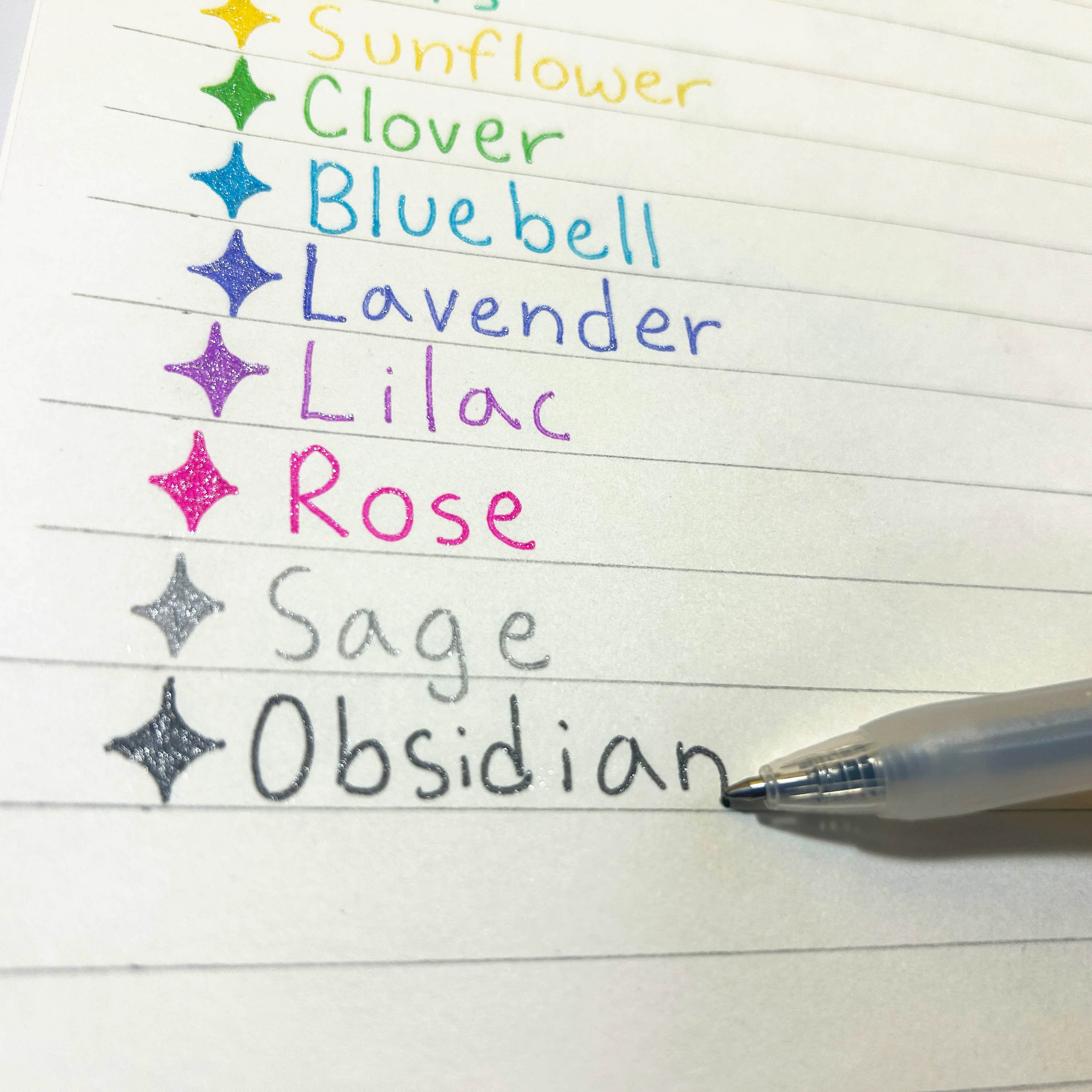 Close up of notepad written with colored swatches focusing on the color "Obsidian" written with a OOLY Oh My Glitter! Retractable Gel Pen