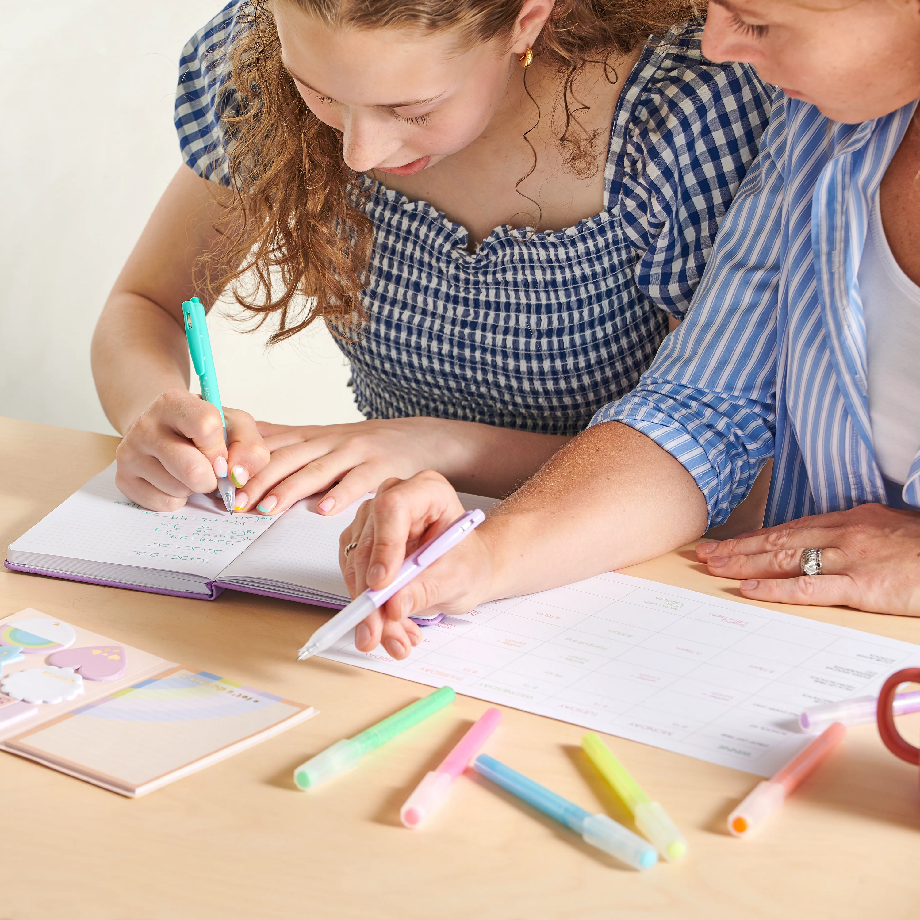Two women writing in notebook with OOLY Oh My Glitter! Retractable Gel Pens