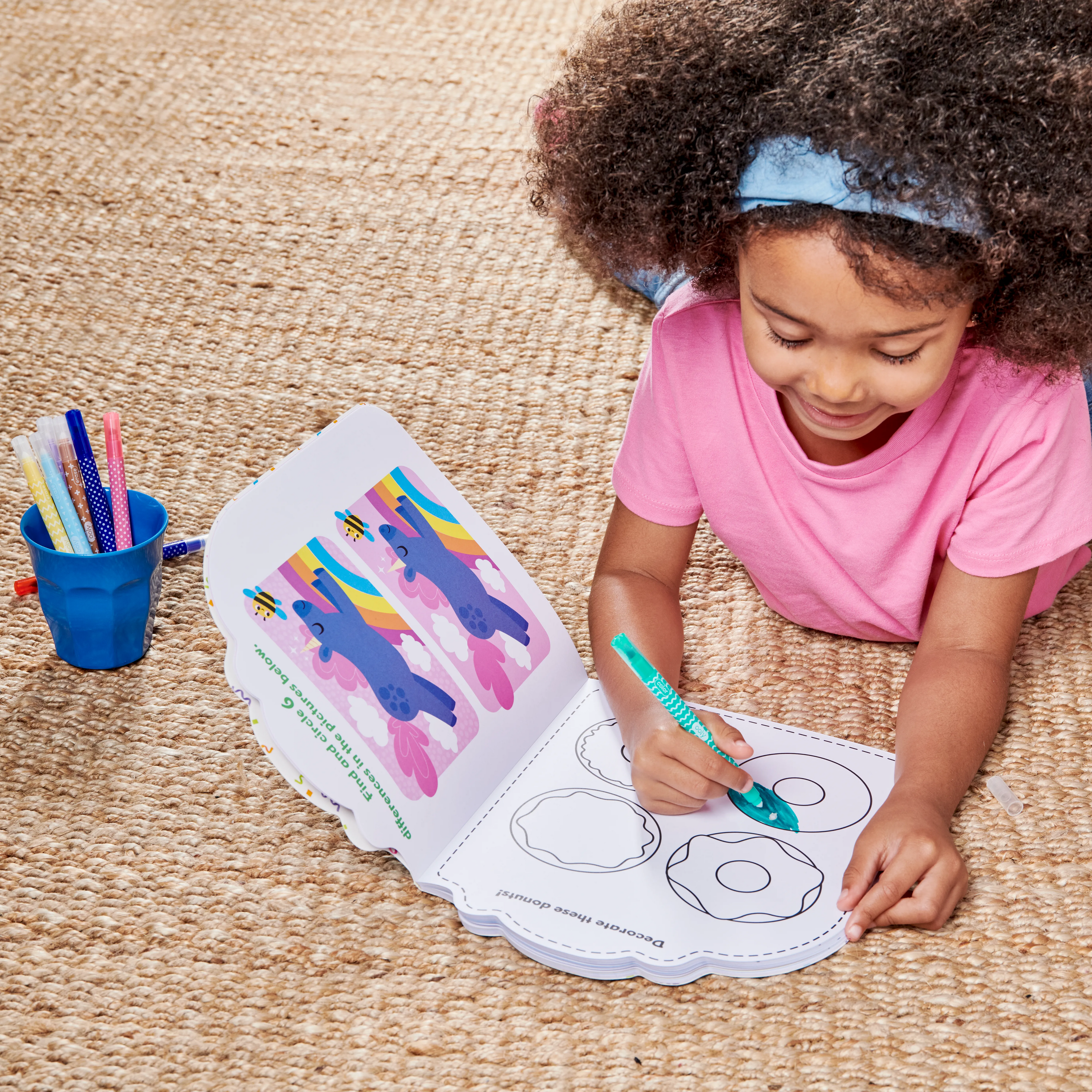 Girl on floor coloring donut in OOLY Playful Pages Activity Book - Games Coloring Stickers - Unicorn Party!