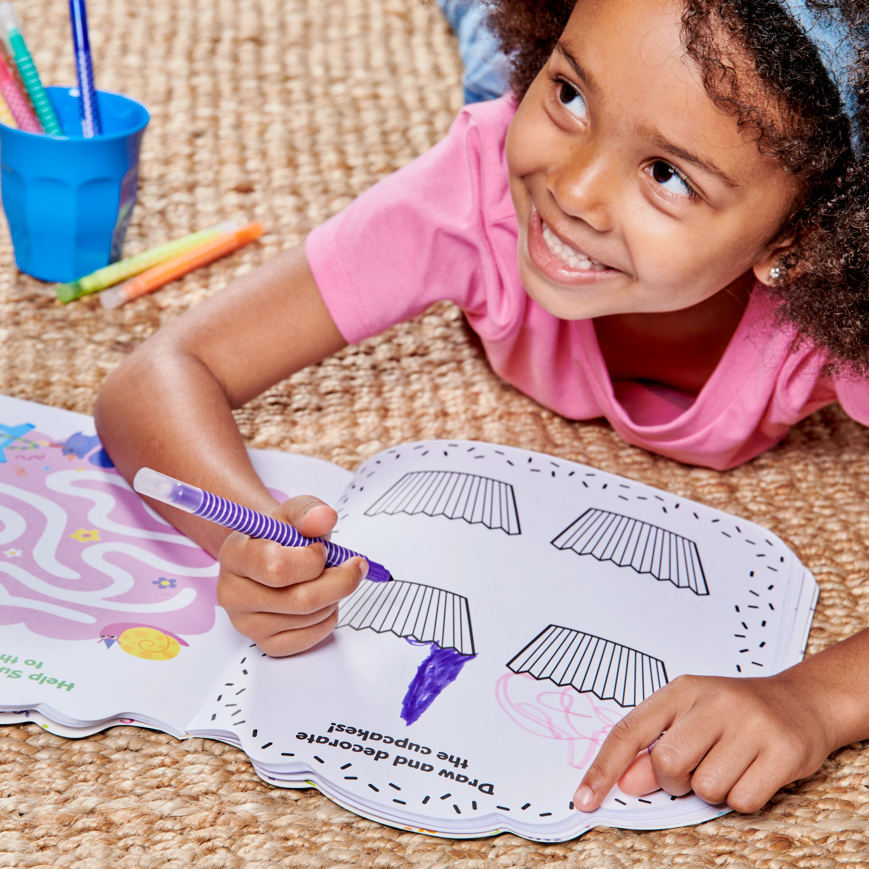 Girl on floor drawing cupcakes in OOLY Playful Pages Activity Book - Games Coloring Stickers - Unicorn Party!