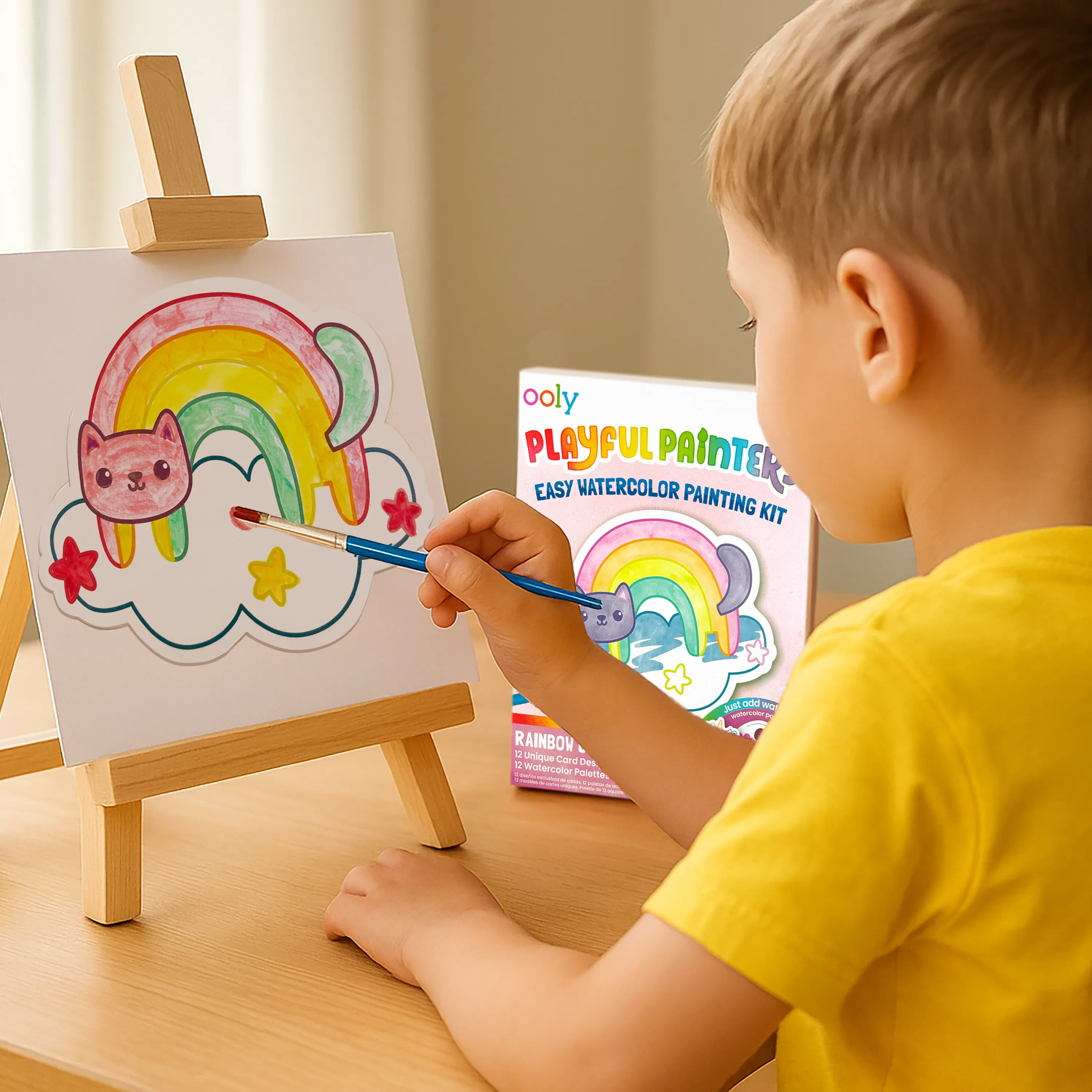 Kid painting rainbow cat on an easel using OOLY Rainbow Cuties Playful Painters Easy Watercolor Painting Kit