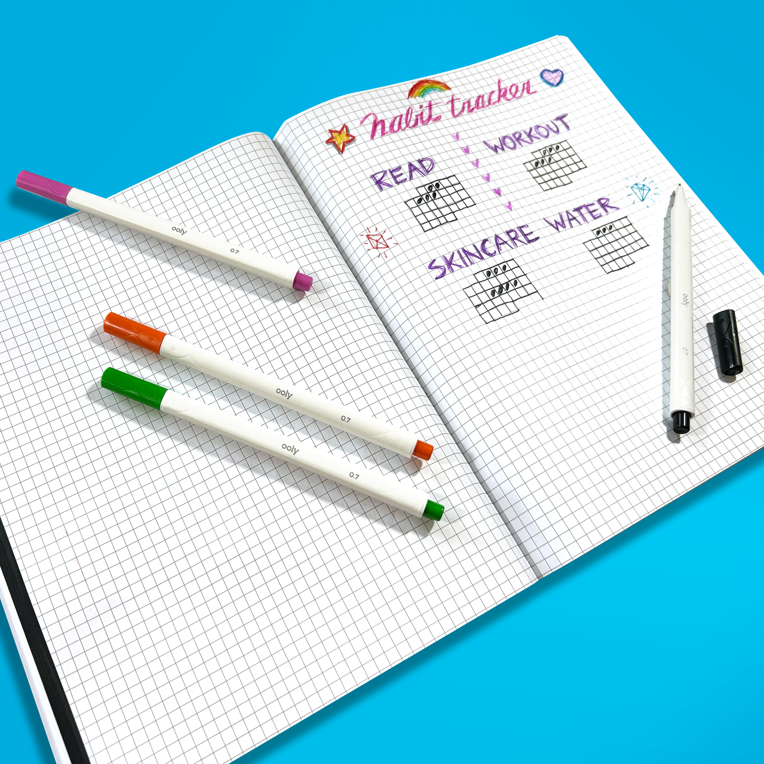 Habit tracker made with OOLY Seriously Fine Tip Markers in a graph paper notebook with a blue background