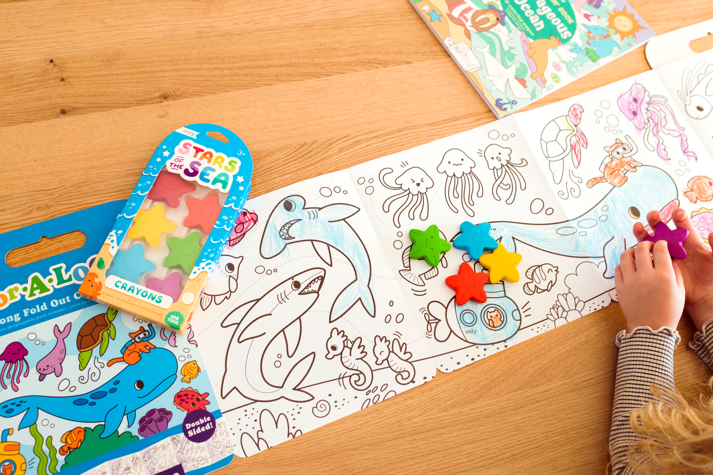 Girl coloring ocean animals in long coloring book with Stars of the Sea Crayons