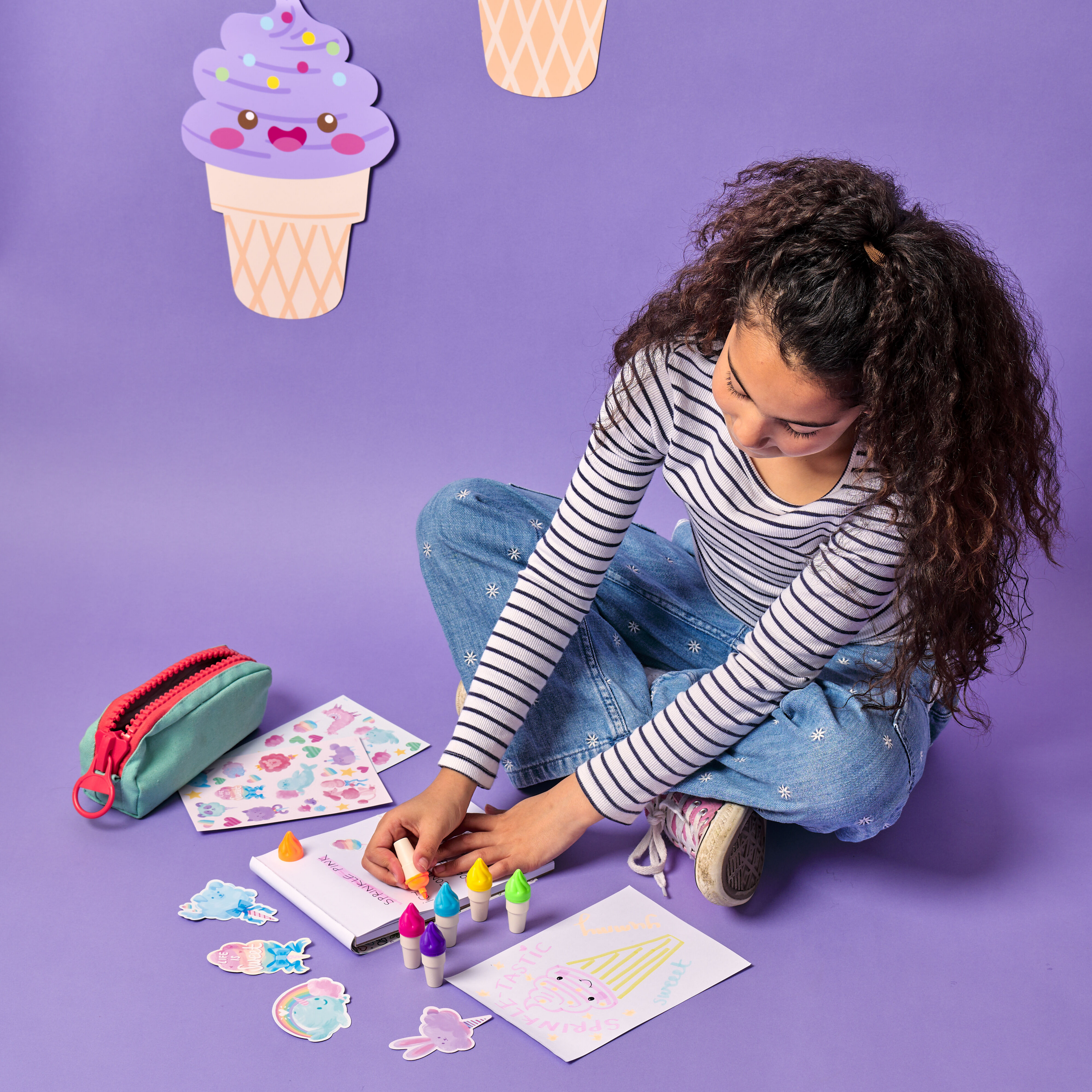Girl highlighting in a sketchbook with OOLY Sweet Scoops Scented Neon Highlighters with colorful stickers on a purple background