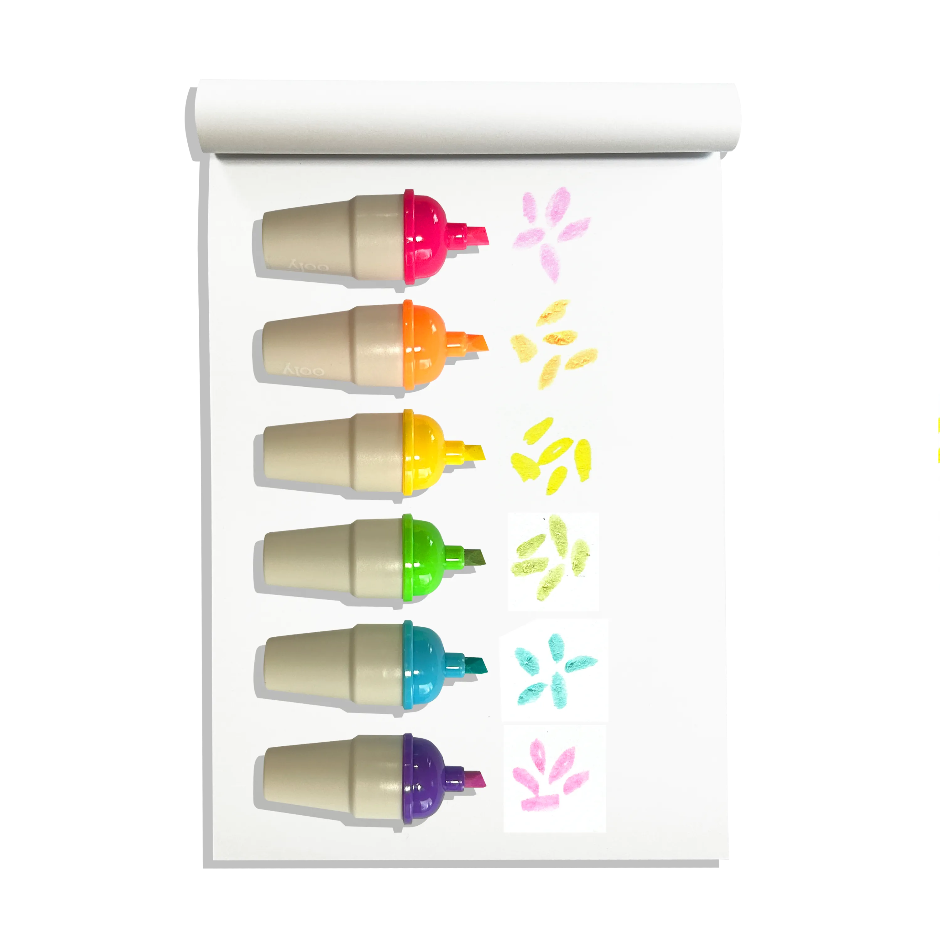 Row of uncapped OOLY Sweet Scoops Scented Neon Highlighters on a white sketchbook with colored swatches