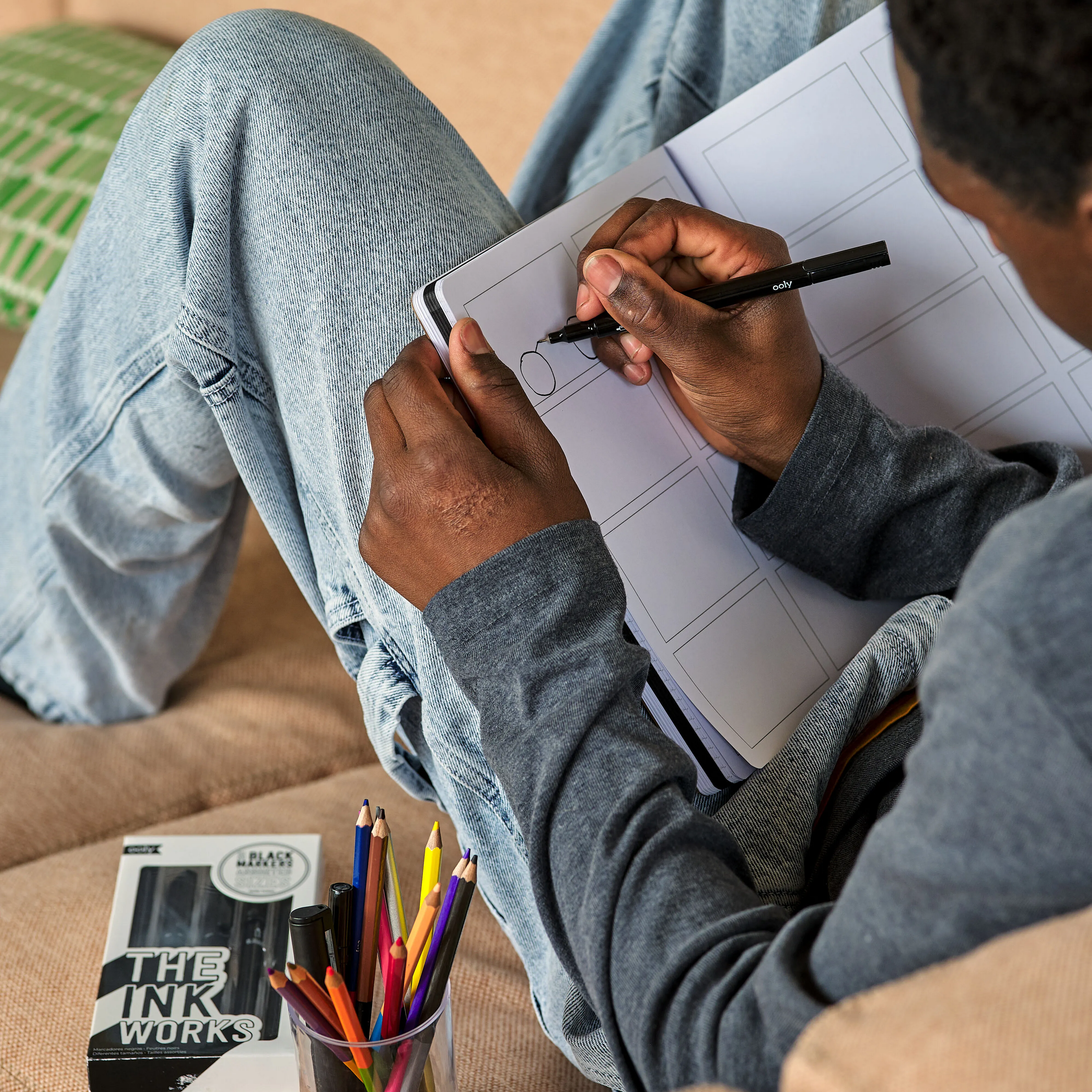 Artist drawing in a comic template in OOLY's The Paper Works Sketchbook with The Ink Works marker