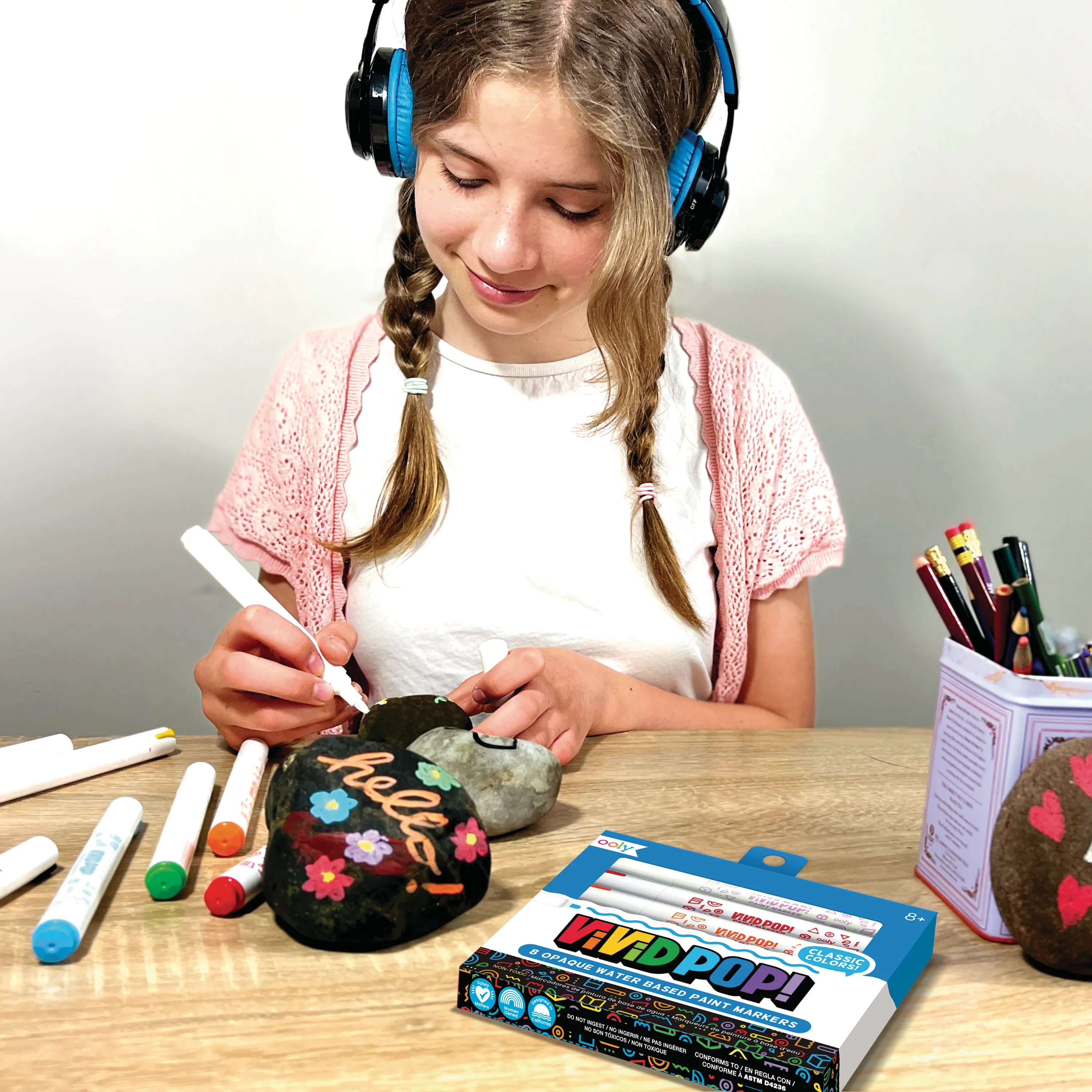 Girl with headphones painting rocks with OOLY Vivid Pop! Water Based Paint Markers