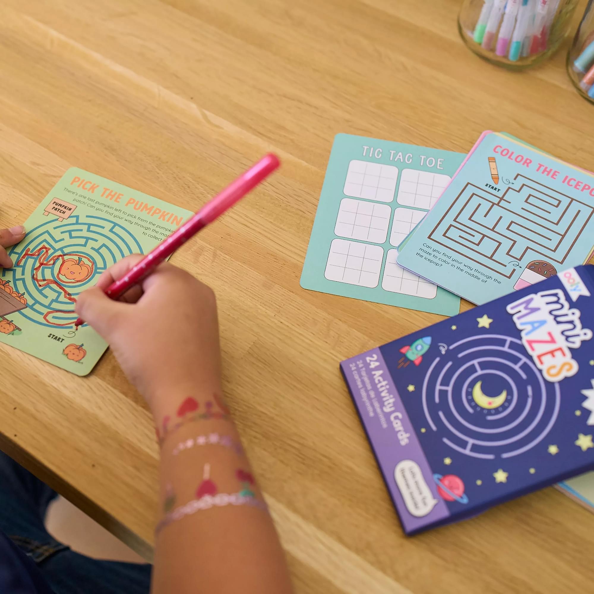 Kid playing OOLY Mini Mazes activity kit on table close up