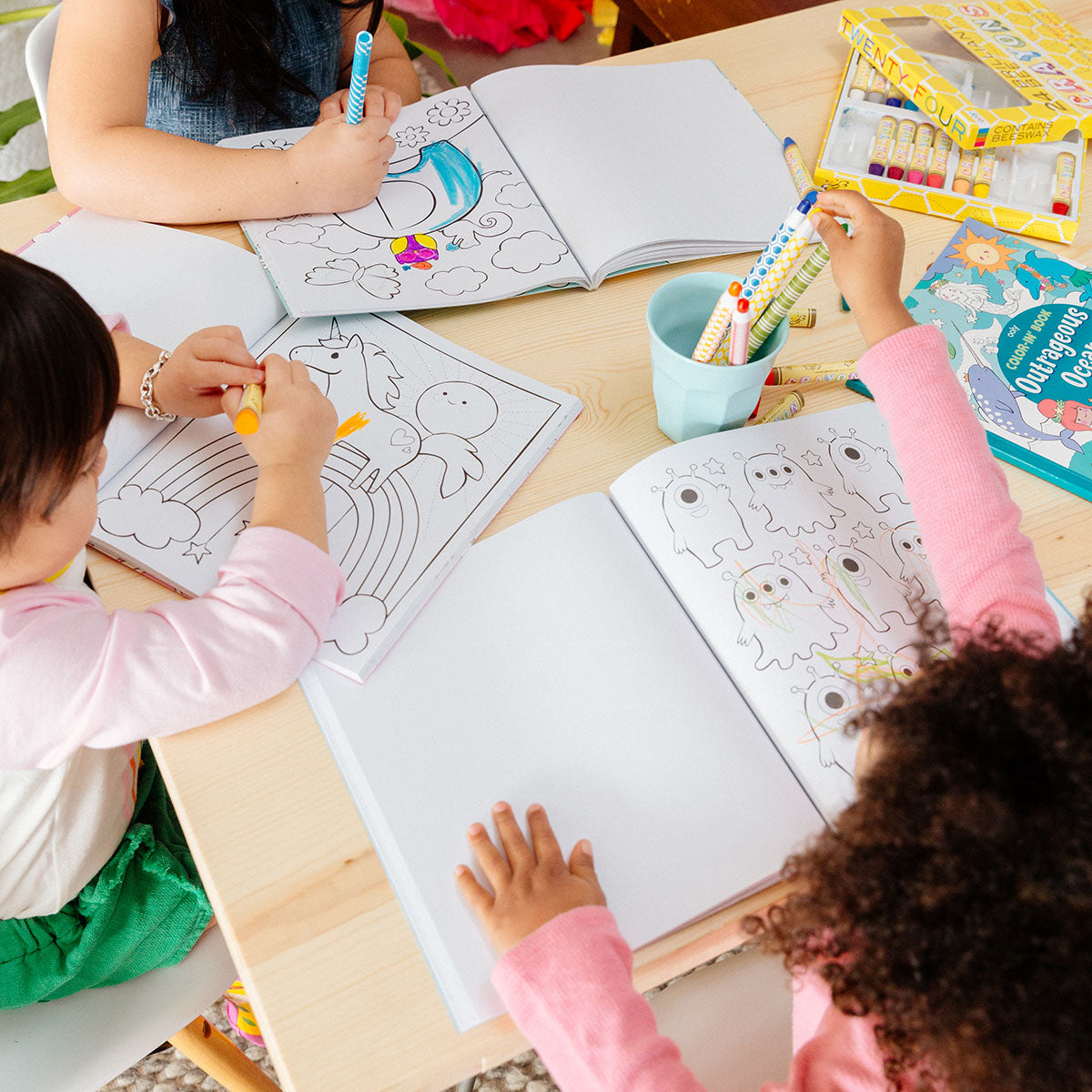 3 kids coloring in an Enchanting Unicorns Coloring Book