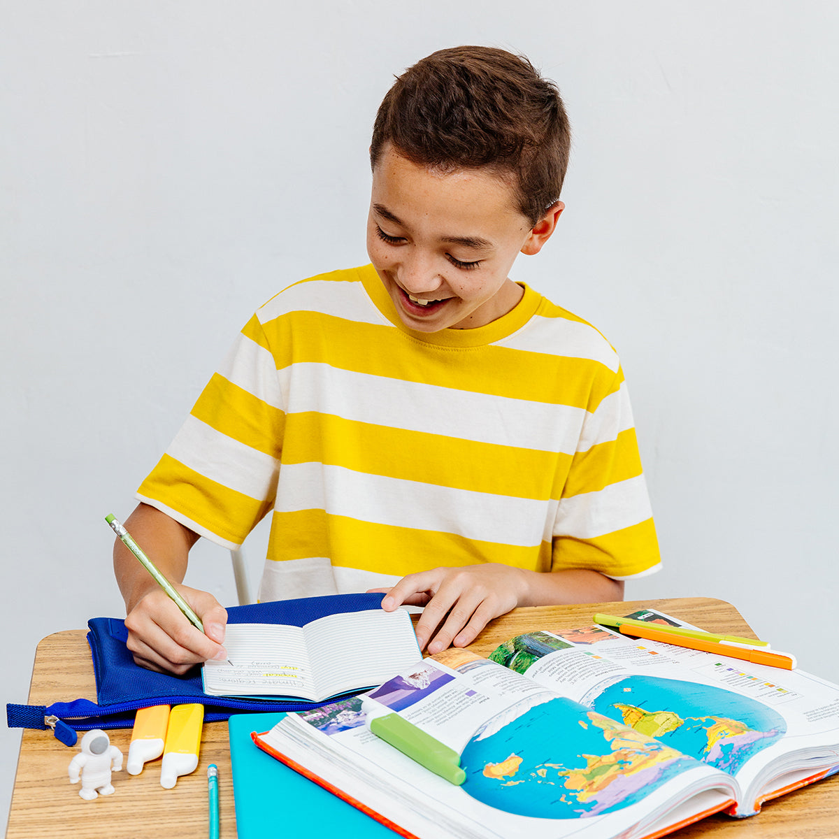 Happy kid sitting at desk and writing with green Stay Sharp Graphite Pencil