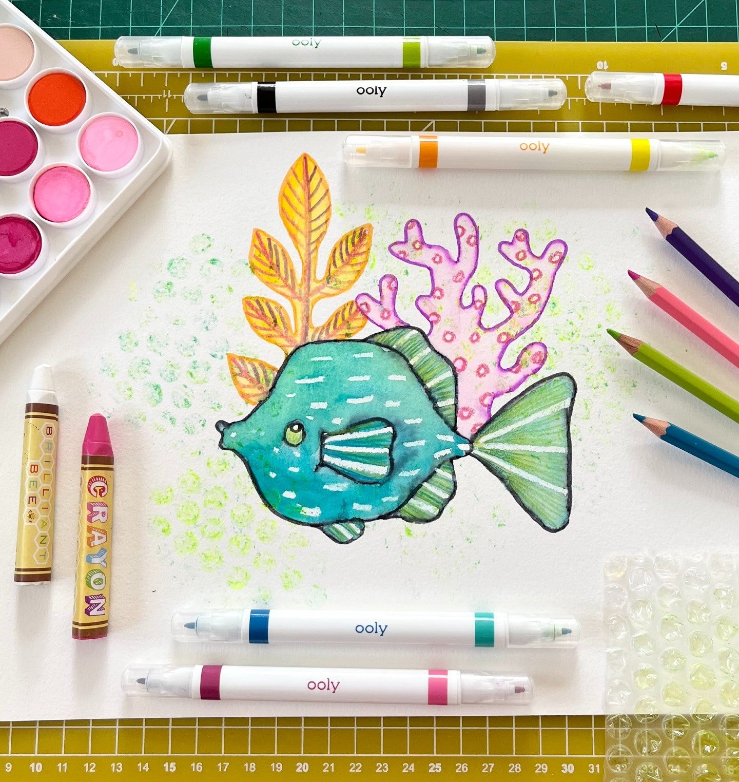 Colorful fish on white paper with markers, crayons and colored pencils on a graph board