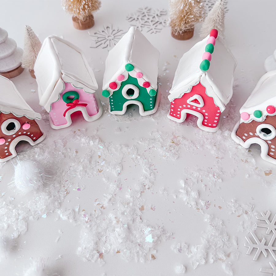 Brown, red, pink, and green clay ginger bread winter houses with fake snow and decorations