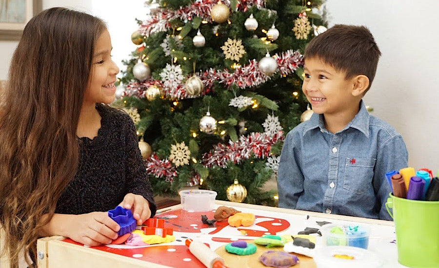girl and boy smiling at each other in front of decorated tree