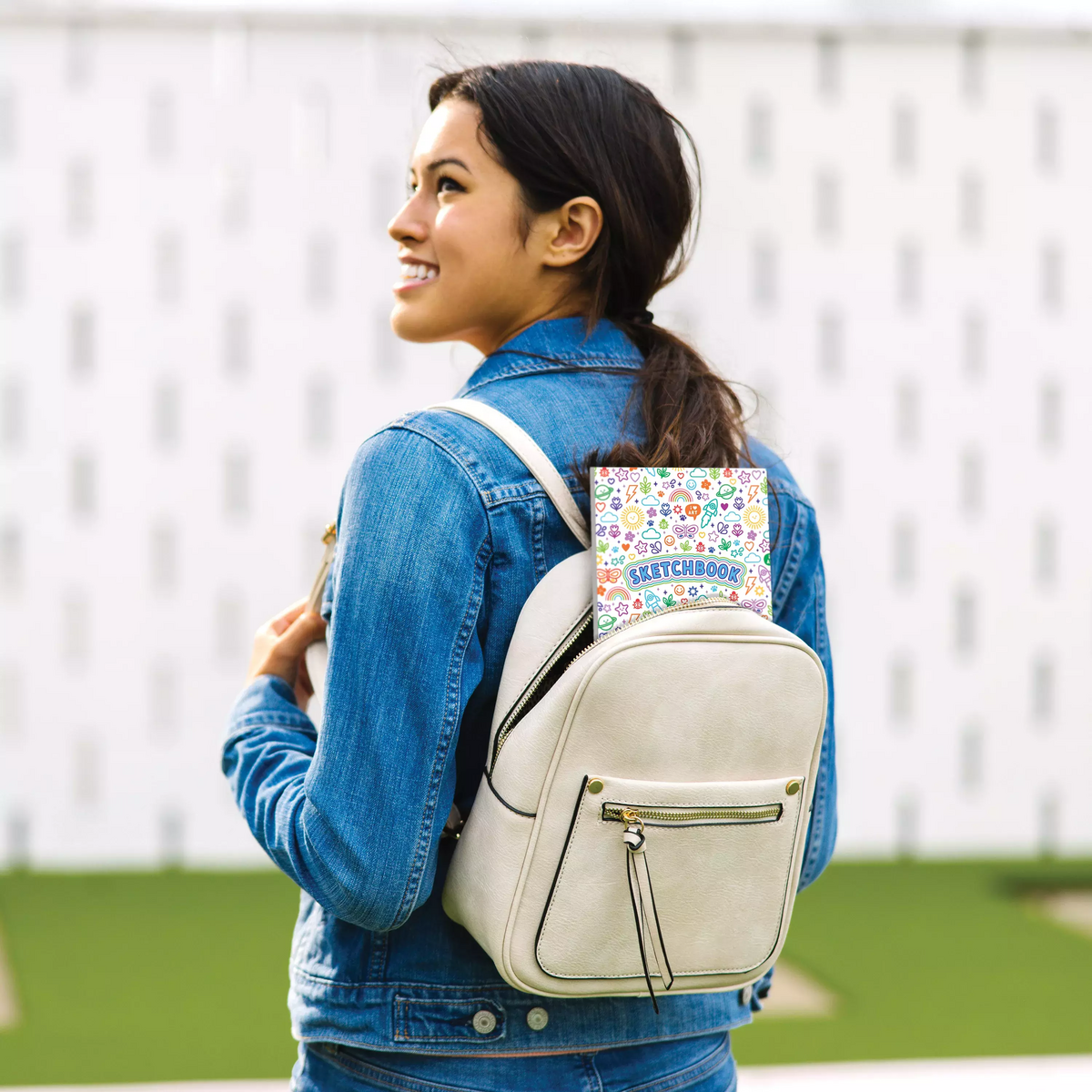 Girl wearing backpack with Colorful Doodles sketchbook