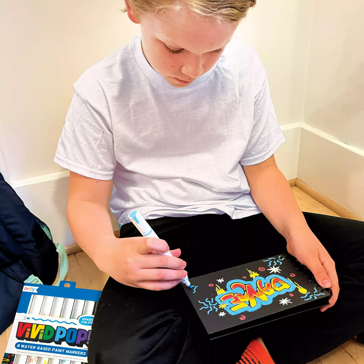 Boy painting with Vivid Pop! Water Based paint markers on black paper