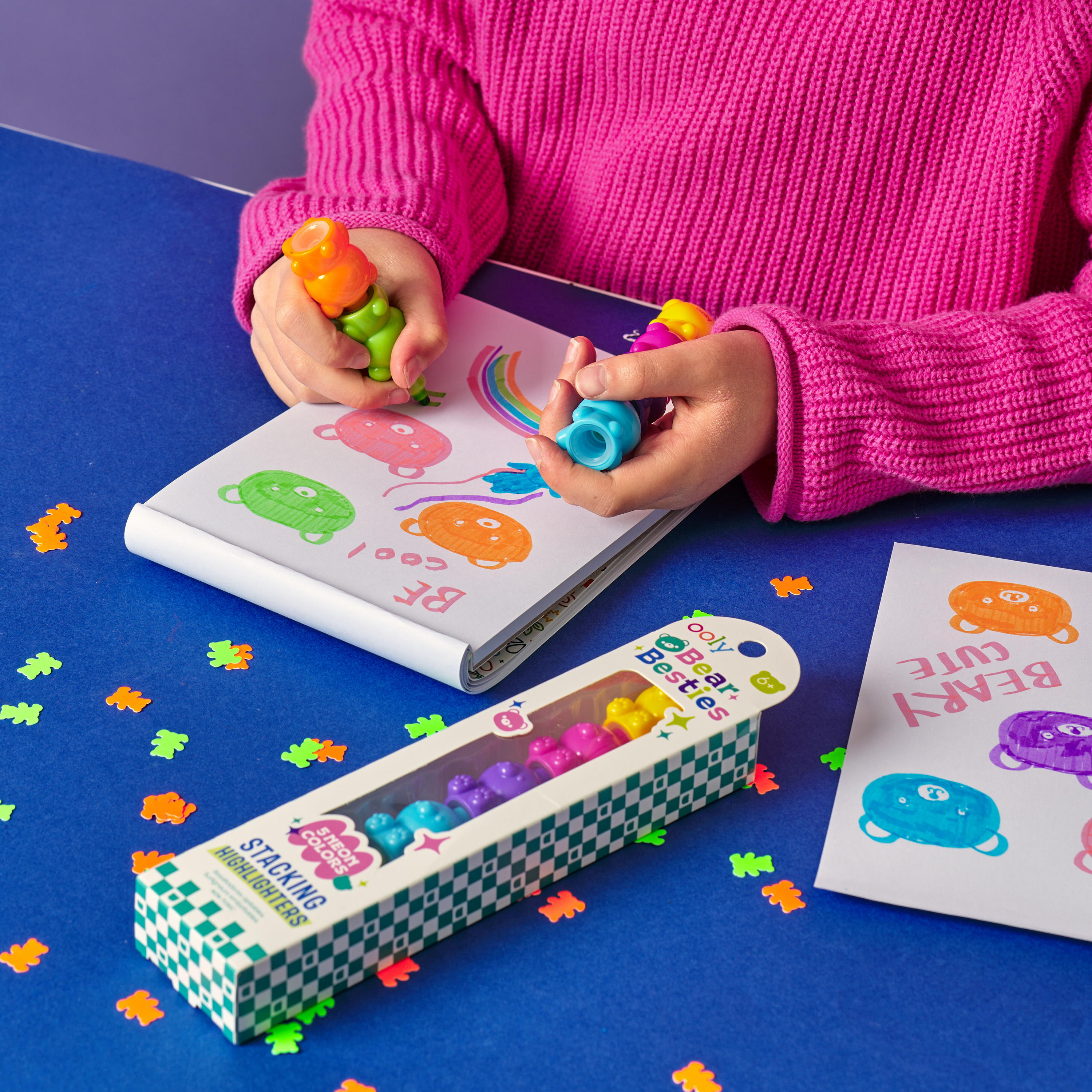 Girl drawing bears in a sketchbook with OOLY Bear Besties Stacking Highlighters on a blue table