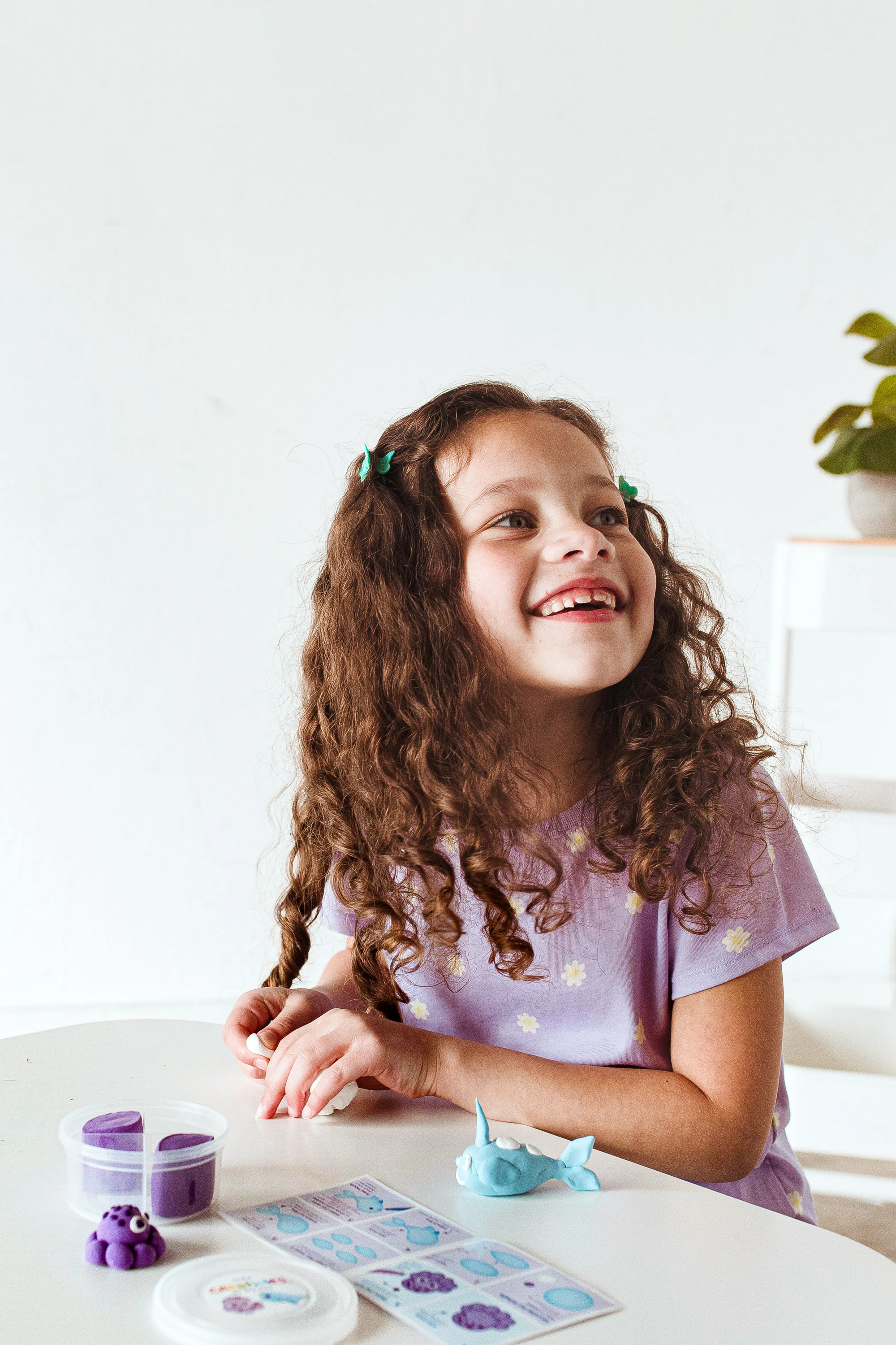 Girl looking up while making animals from OOLY Creatibles Mini Air Dry Clay Kit - Ocean BFFs
