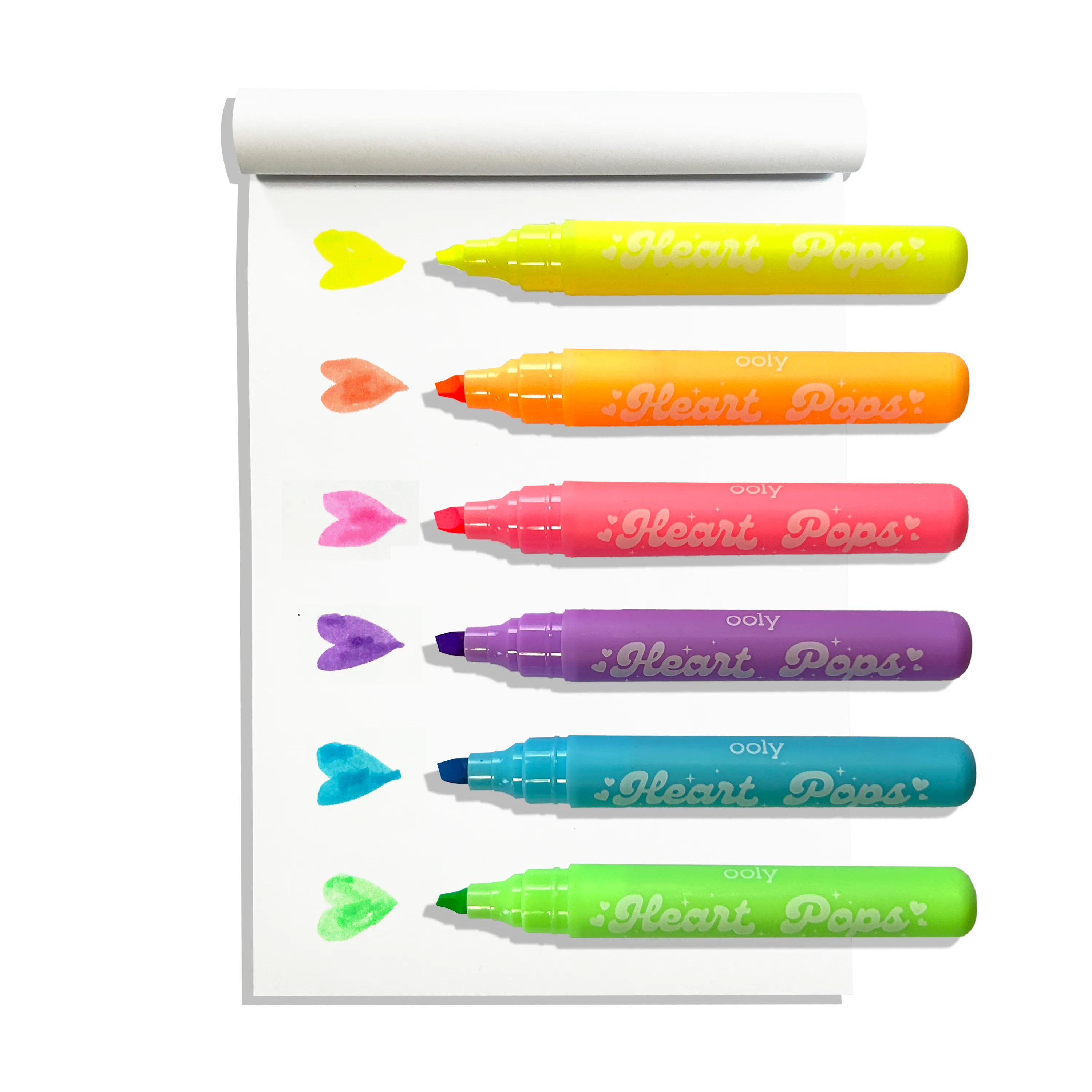 White sketchbook with row of uncapped OOLY Heart Pops Neon Highlighters with heart swatches on white background