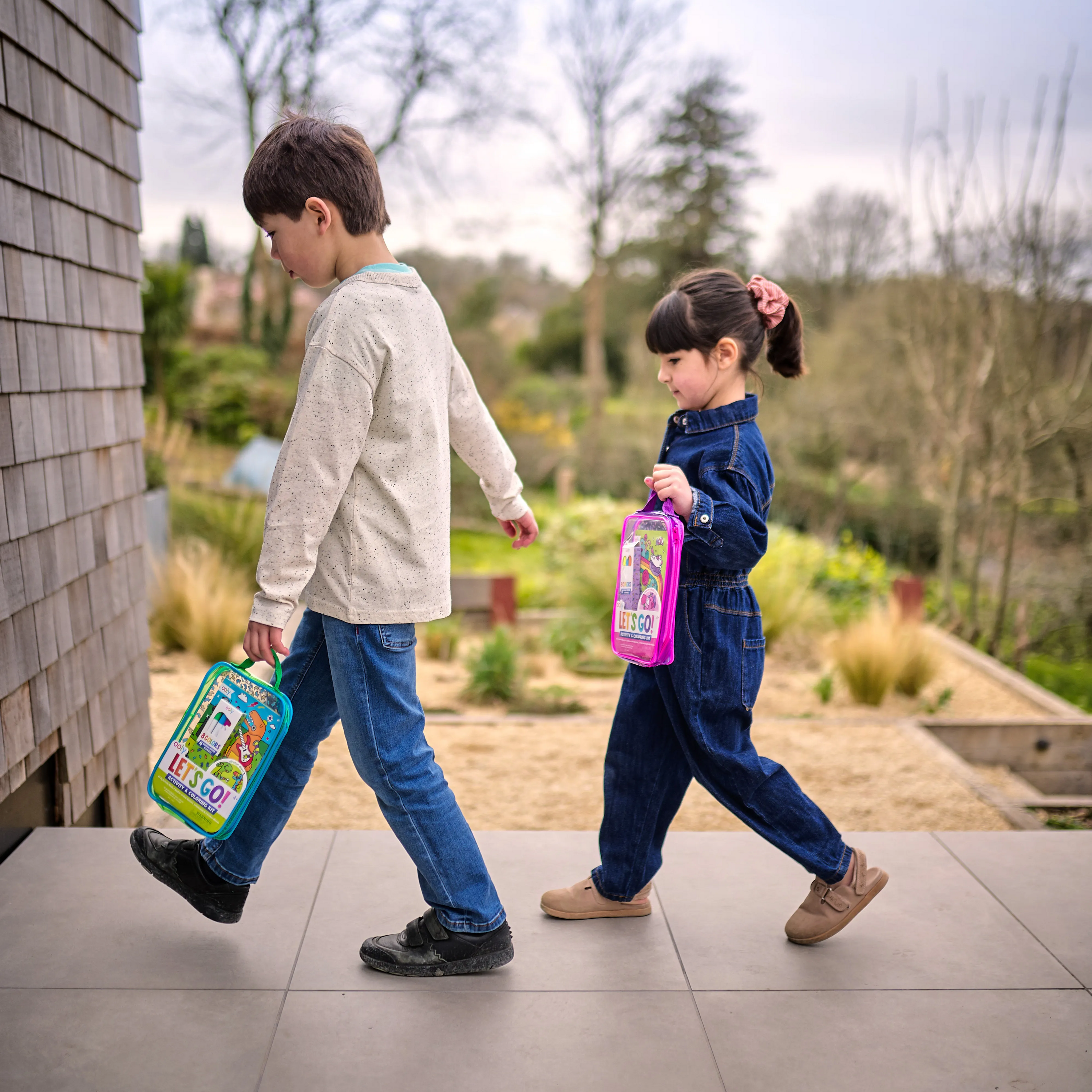 Two kids walking on sidewalk each holding an Let’s Go! Activity & Coloring Kit