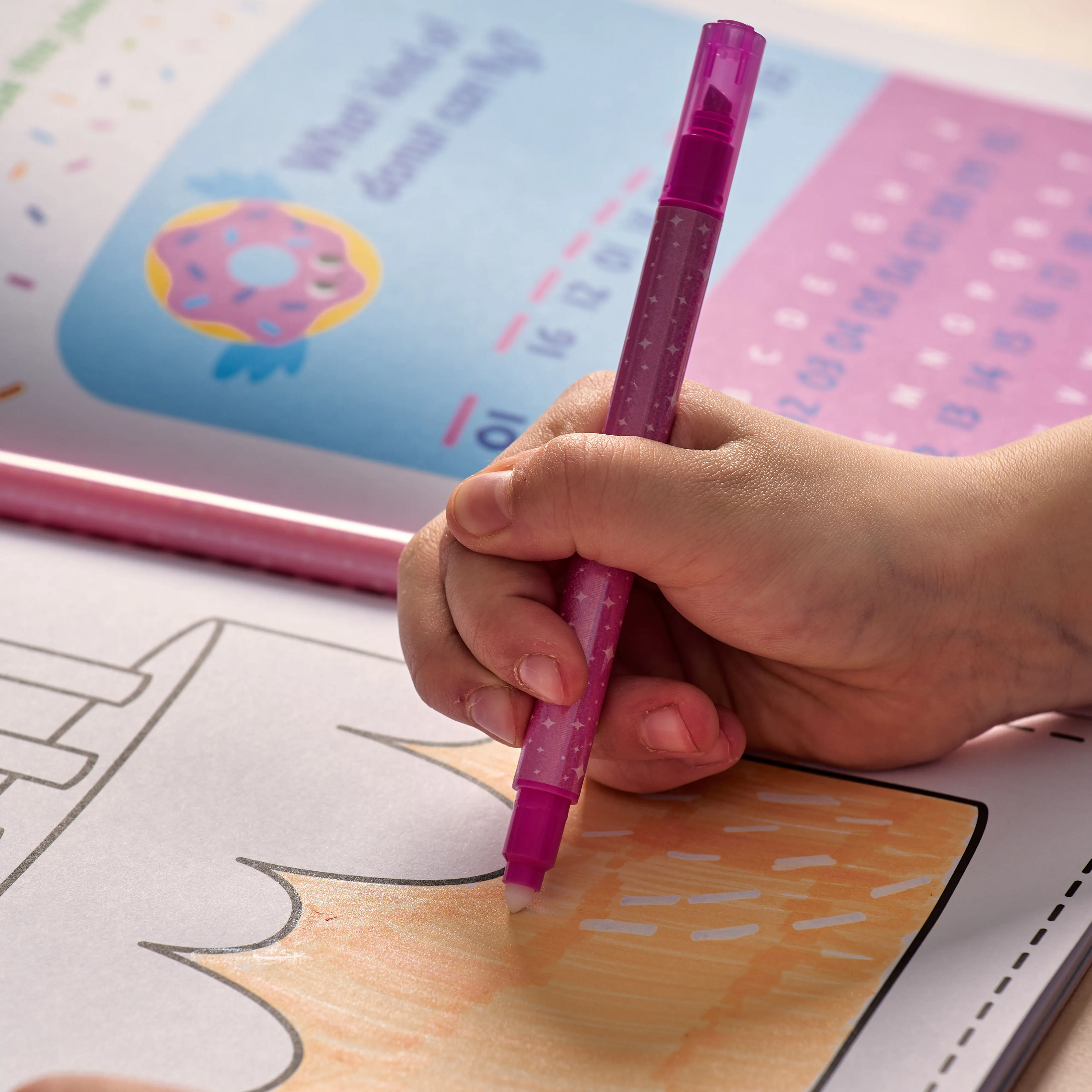 Girl making erased marker textures in birthday cake coloring page with an OOLY Make No Mistake! Glittery Erasable Marker