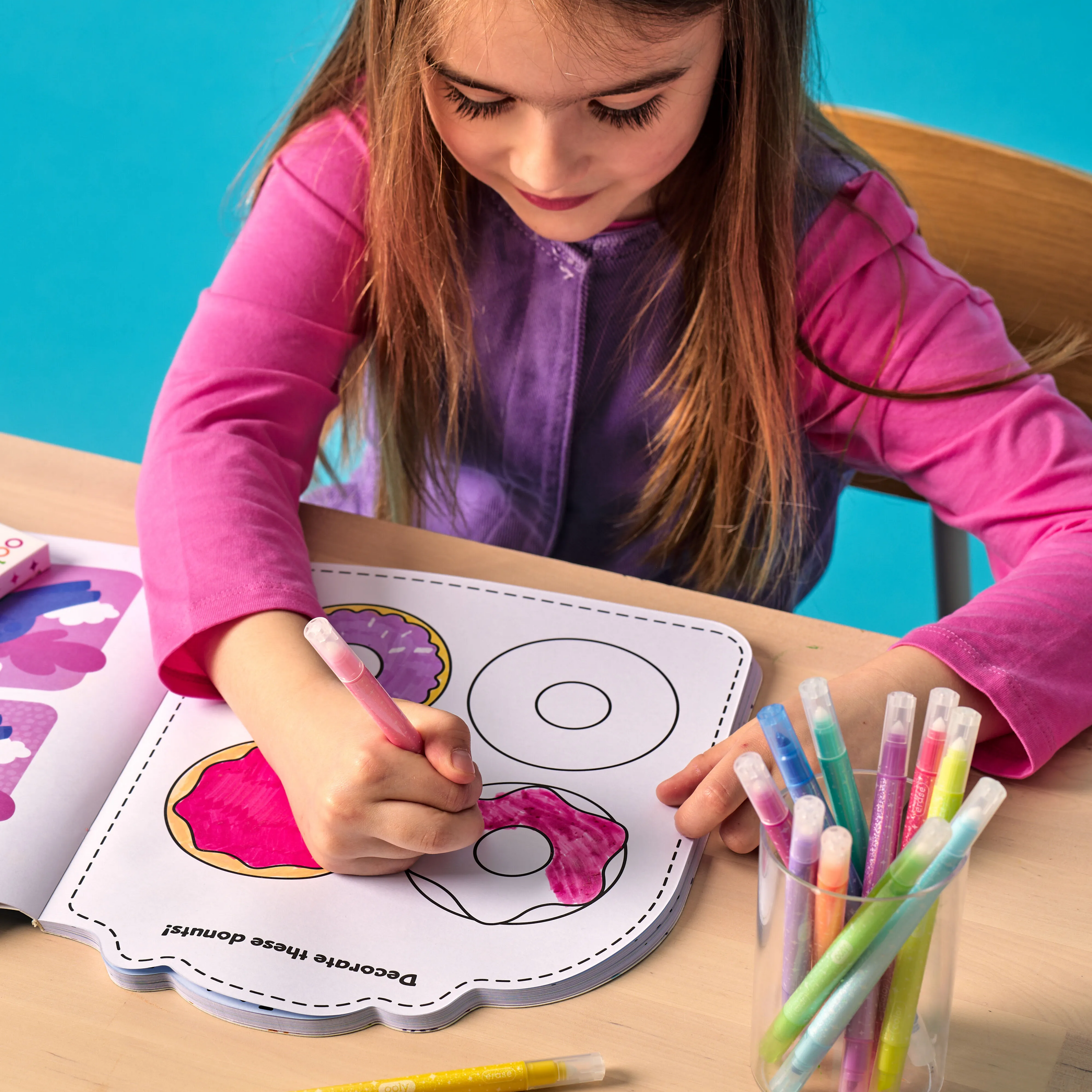 Girl coloring in a donut coloring page with an OOLY Make No Mistake! Glittery Erasable Markers