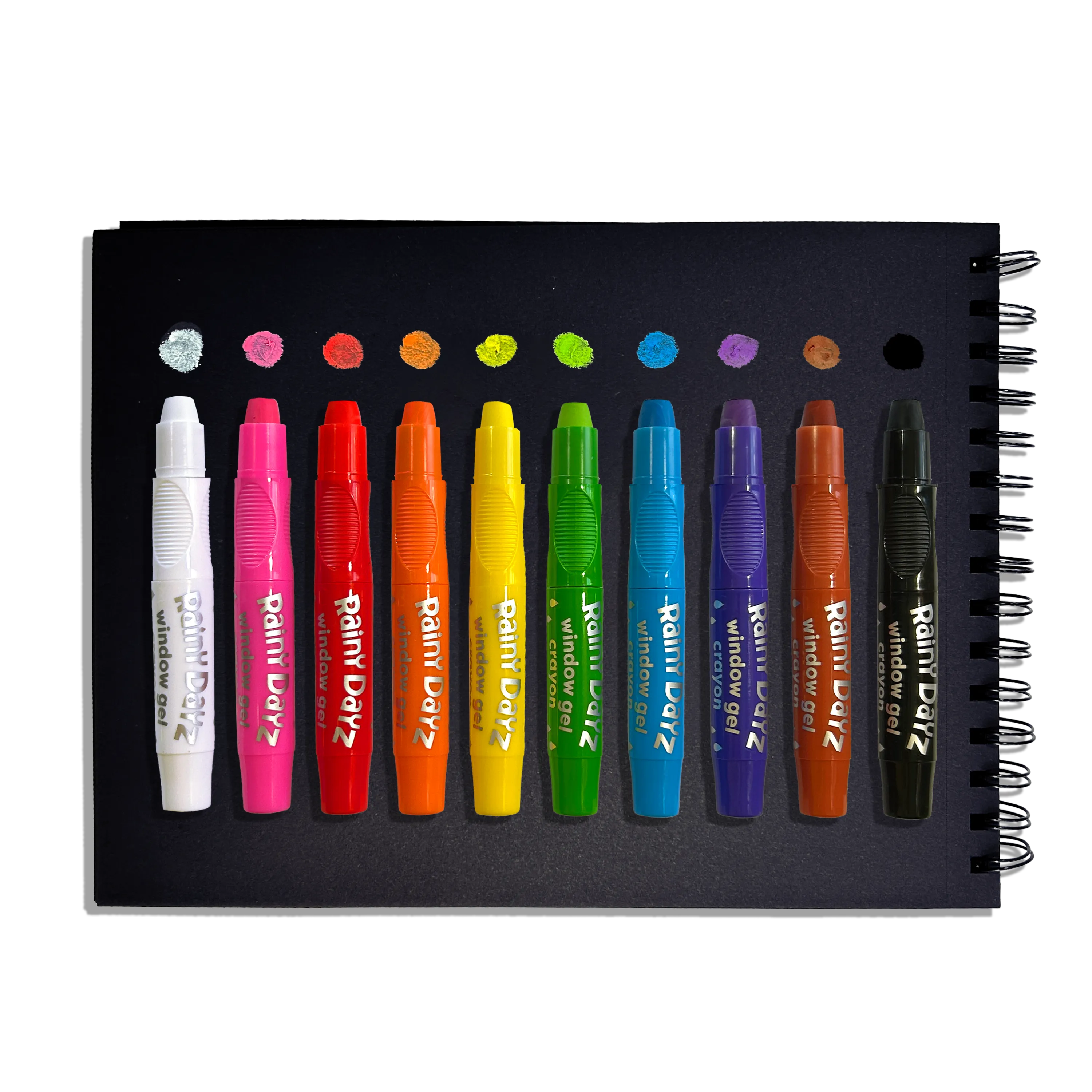 Row of uncapped OOLY Rainy Dayz Window Gel Crayons on a black paper sketchbook with swatches on a white background