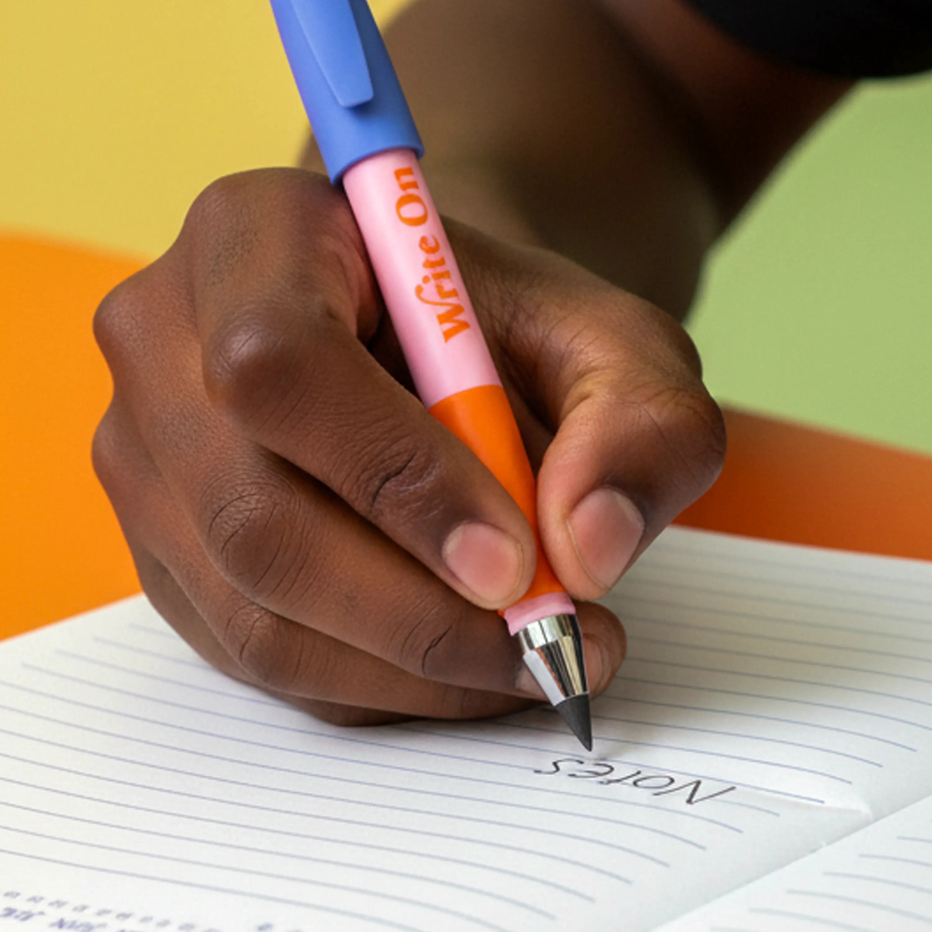Close up of a kid writing the word "Notes" in an OOLY Write On Notebook