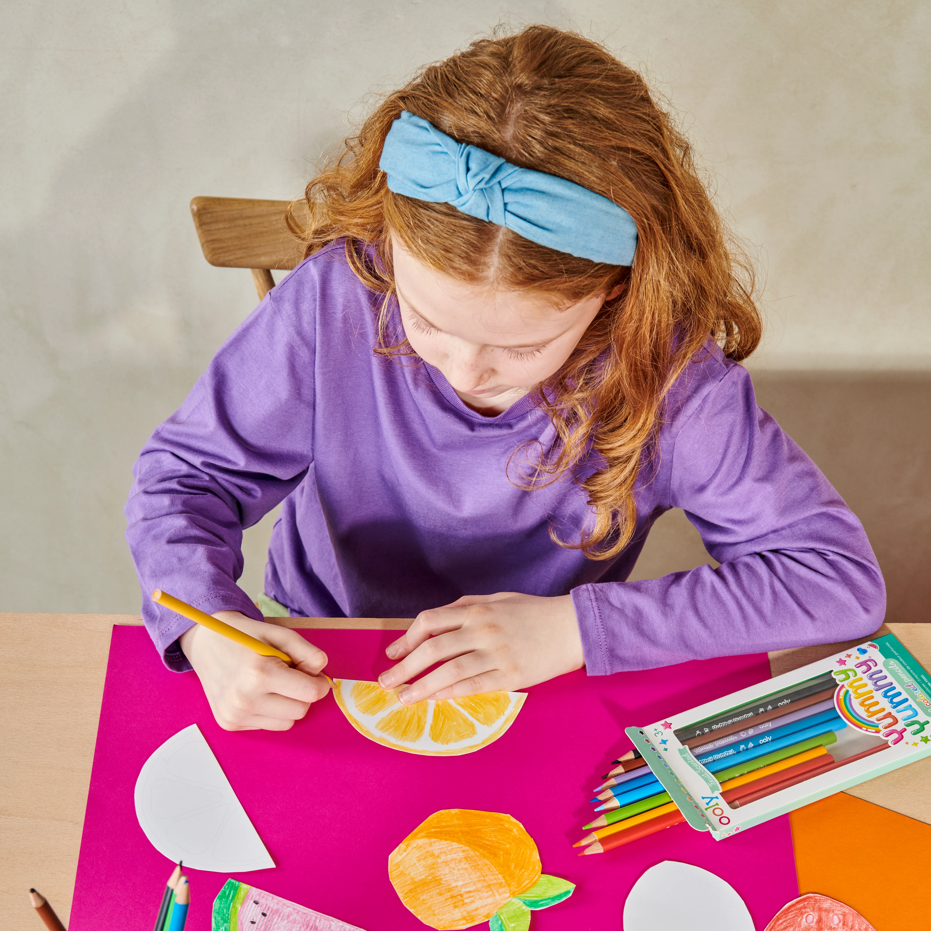 High angle of girl at a table coloring lemon wedge with OOLY Yummy Yummy Fruit Scented Colored Pencils