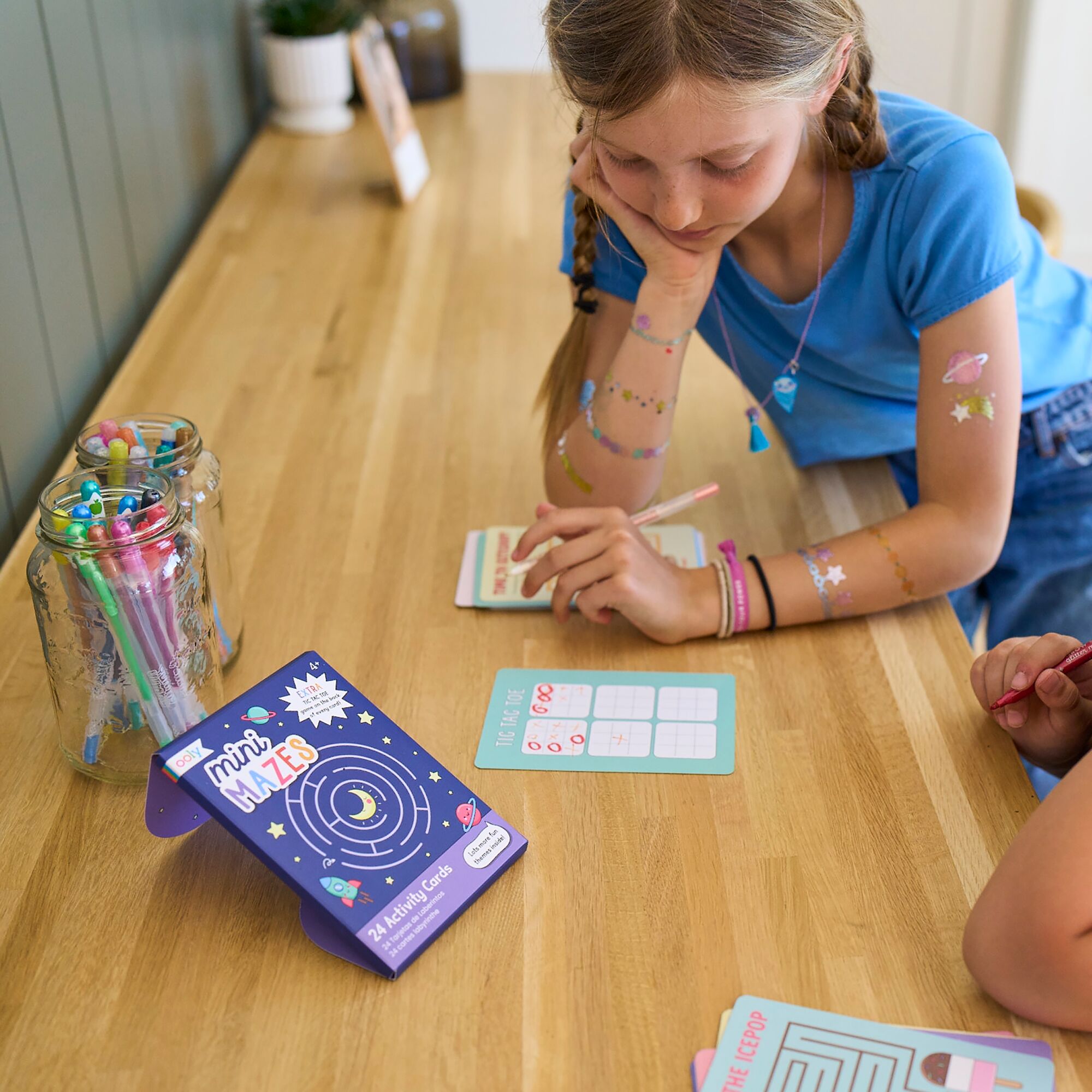 Girl playing OOLY Mini Mazes activity kit on table