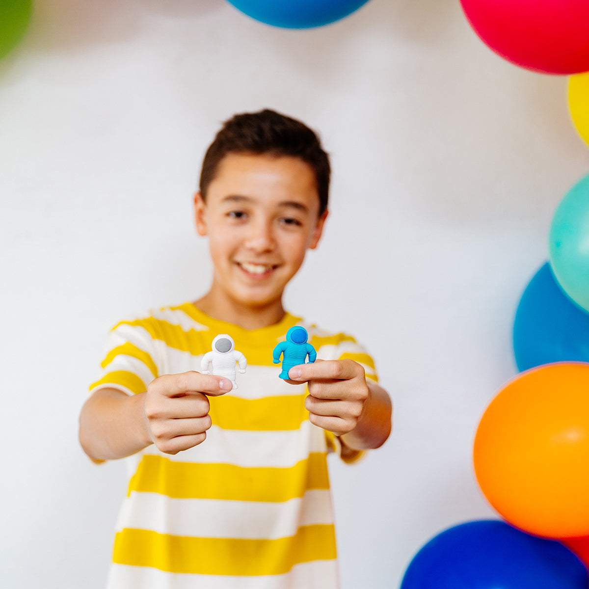 Smiling boy holding up white and blue astronaut erasers