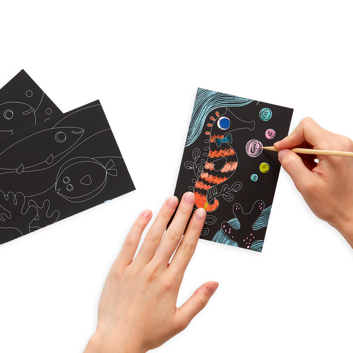 hands drawing on Friendly Fish Scratch and Scribble Mini Scratch Art Kit