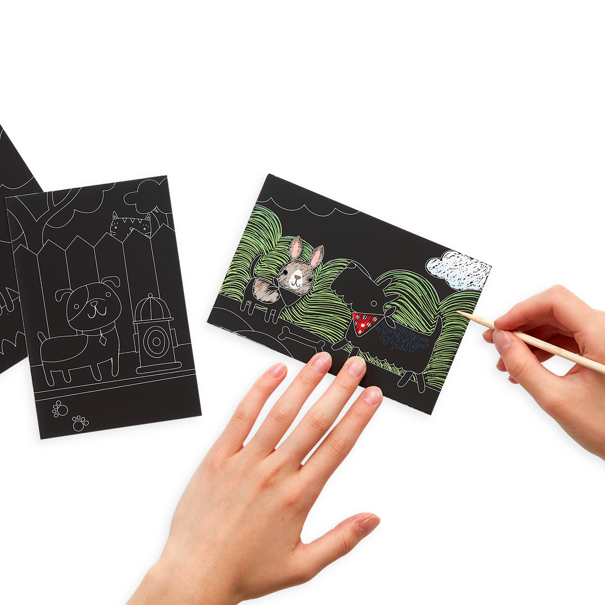 Hands scratching the Playful Pups Scratch and Scribble Mini Scratch Art Kit with the included wooden stylus